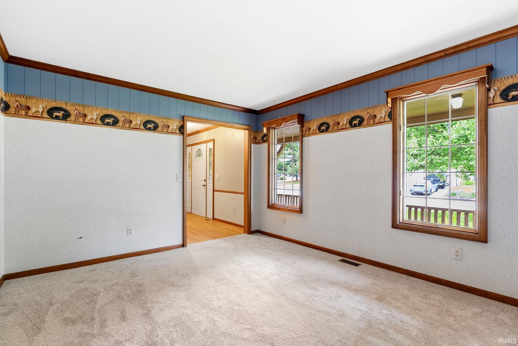 Carpeted room featuring two large windows with wood trim and muntins