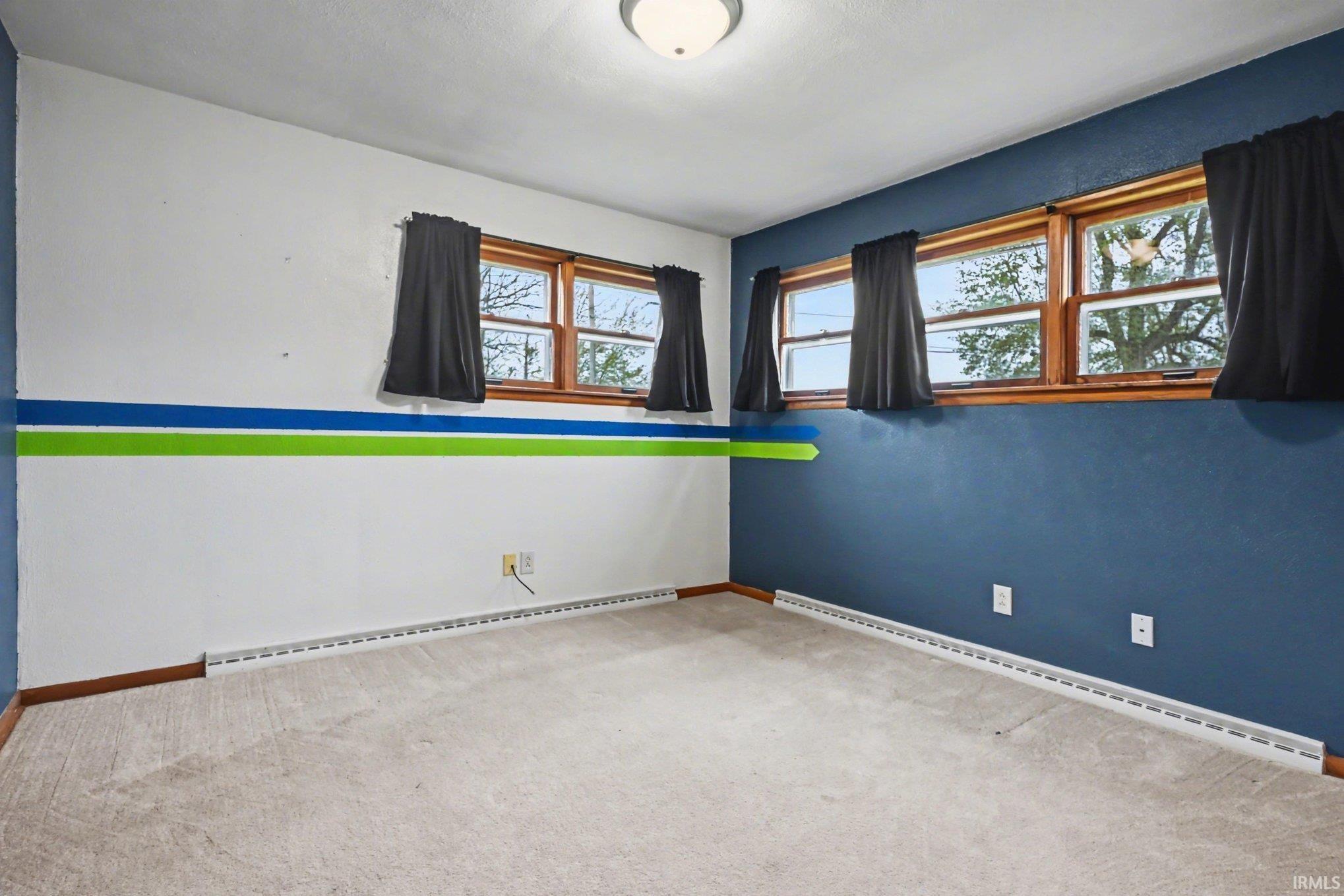Carpeted room featuring a ceiling-mounted light fixture and wood-framed windows