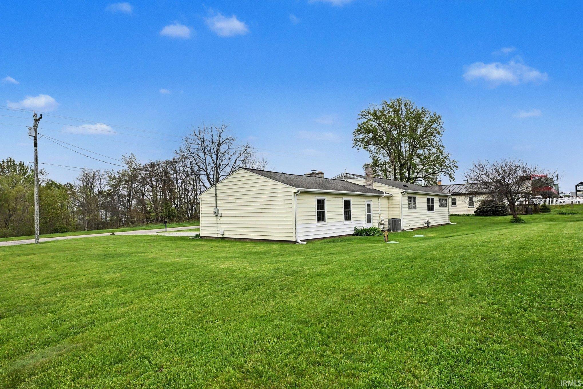Expansive green lawn surrounds a single-story dwelling with light-colored siding