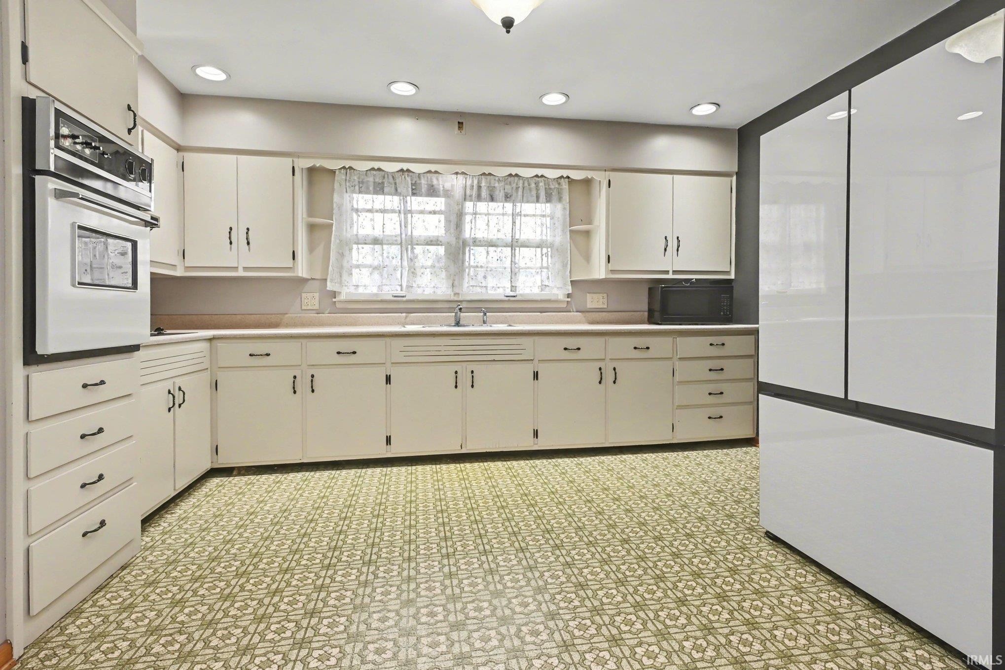 Kitchen featuring extensive cabinetry, patterned flooring, a wall-mounted oven, recessed lighting, and a white refrigerator