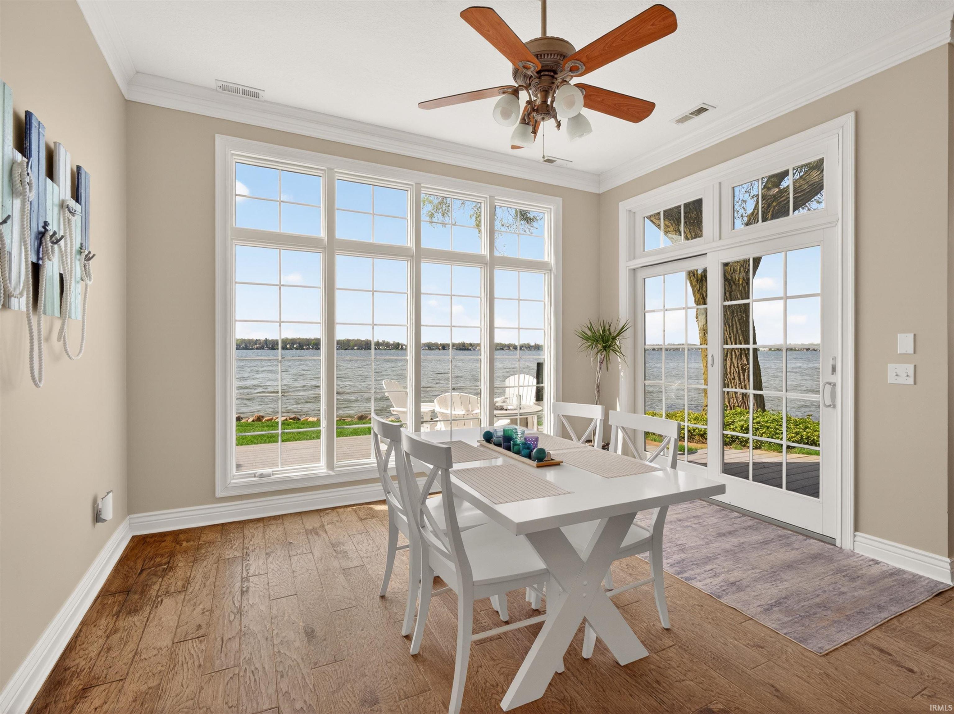 Dining area featuring a water view, ornamental molding, a ceiling fan, and light wood-type flooring