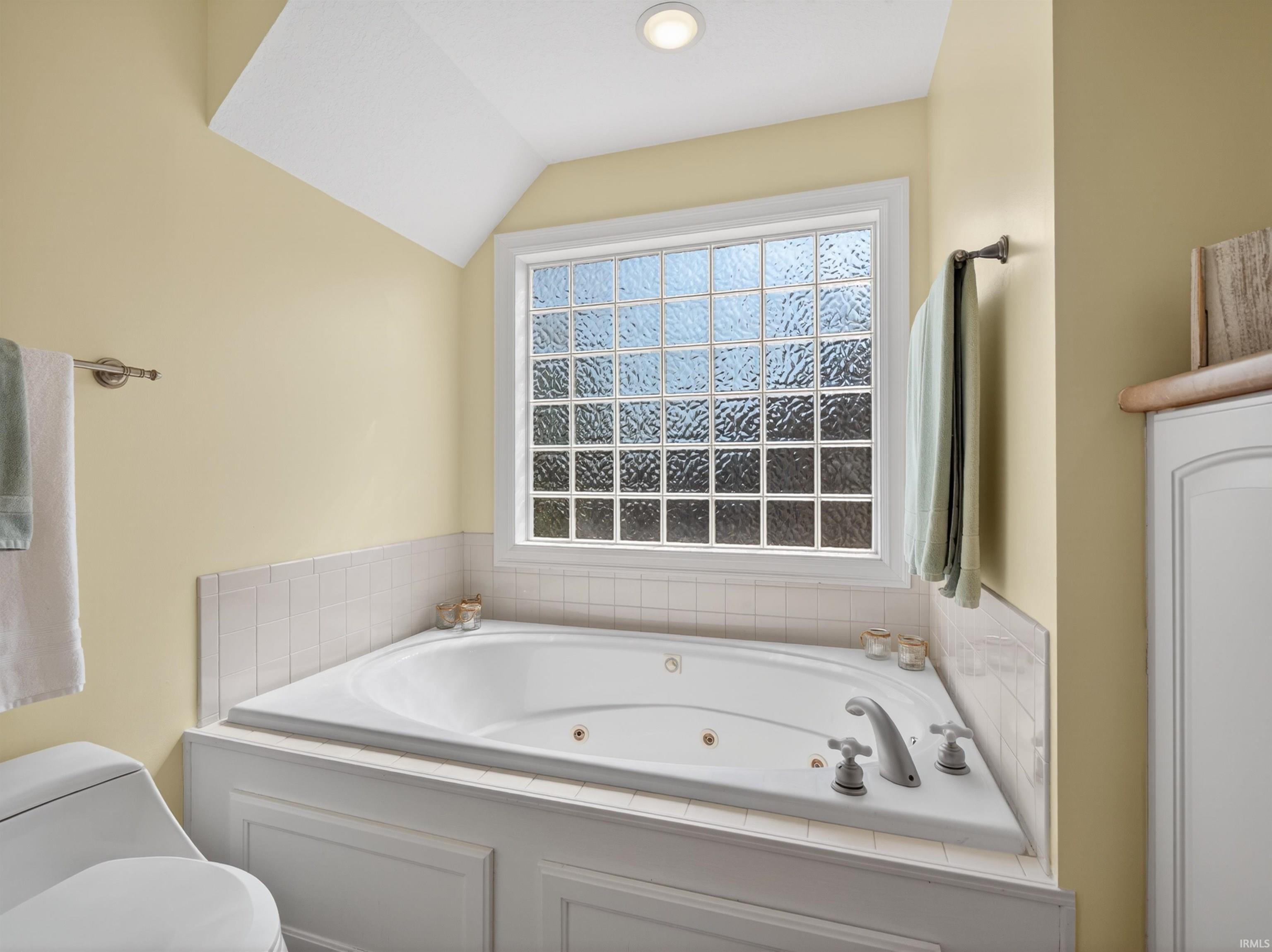 Bathroom with a tub with jets and lofted ceiling