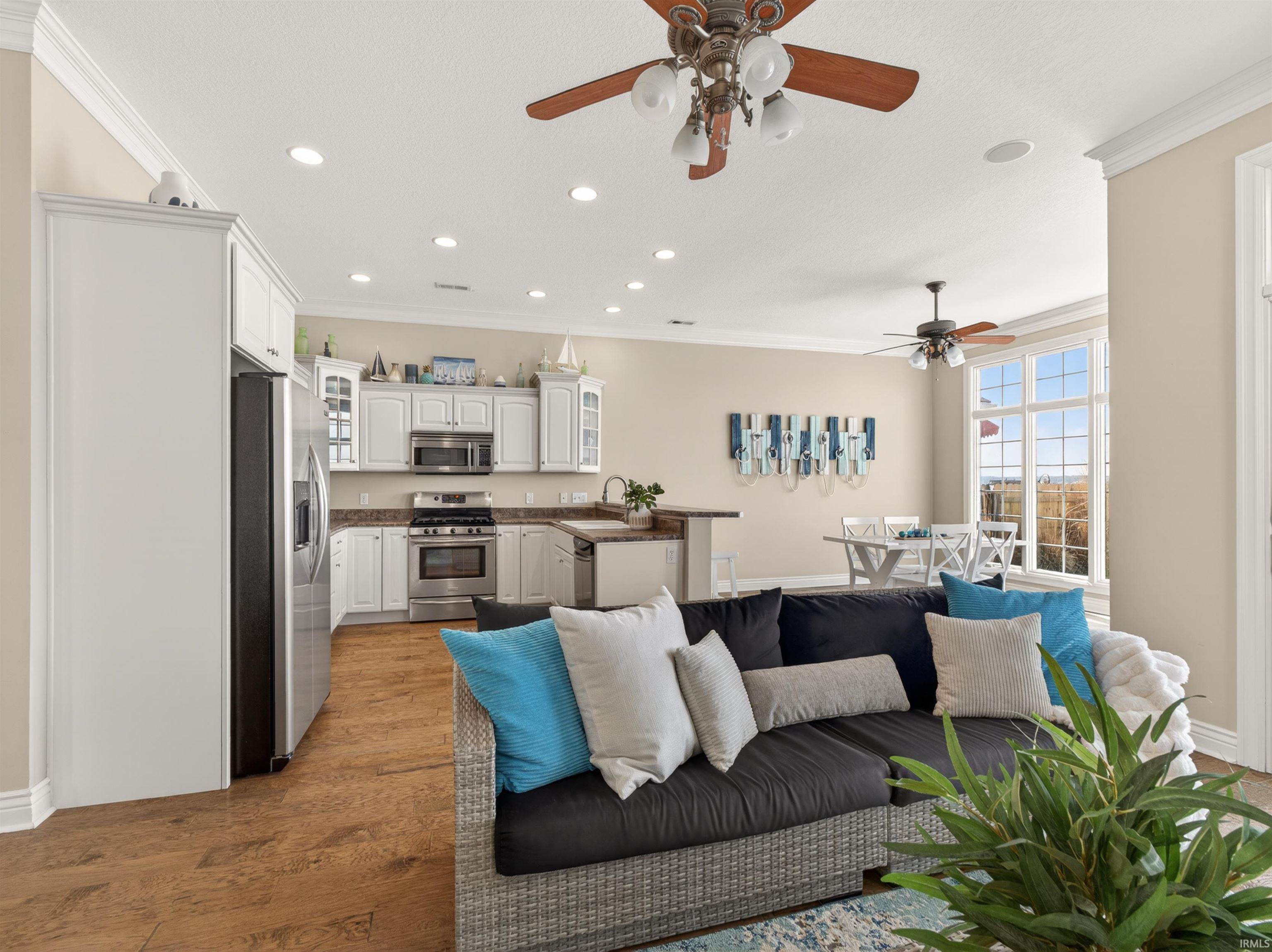 Living room featuring ornamental molding, ceiling fan, light wood-style floors, and recessed lighting