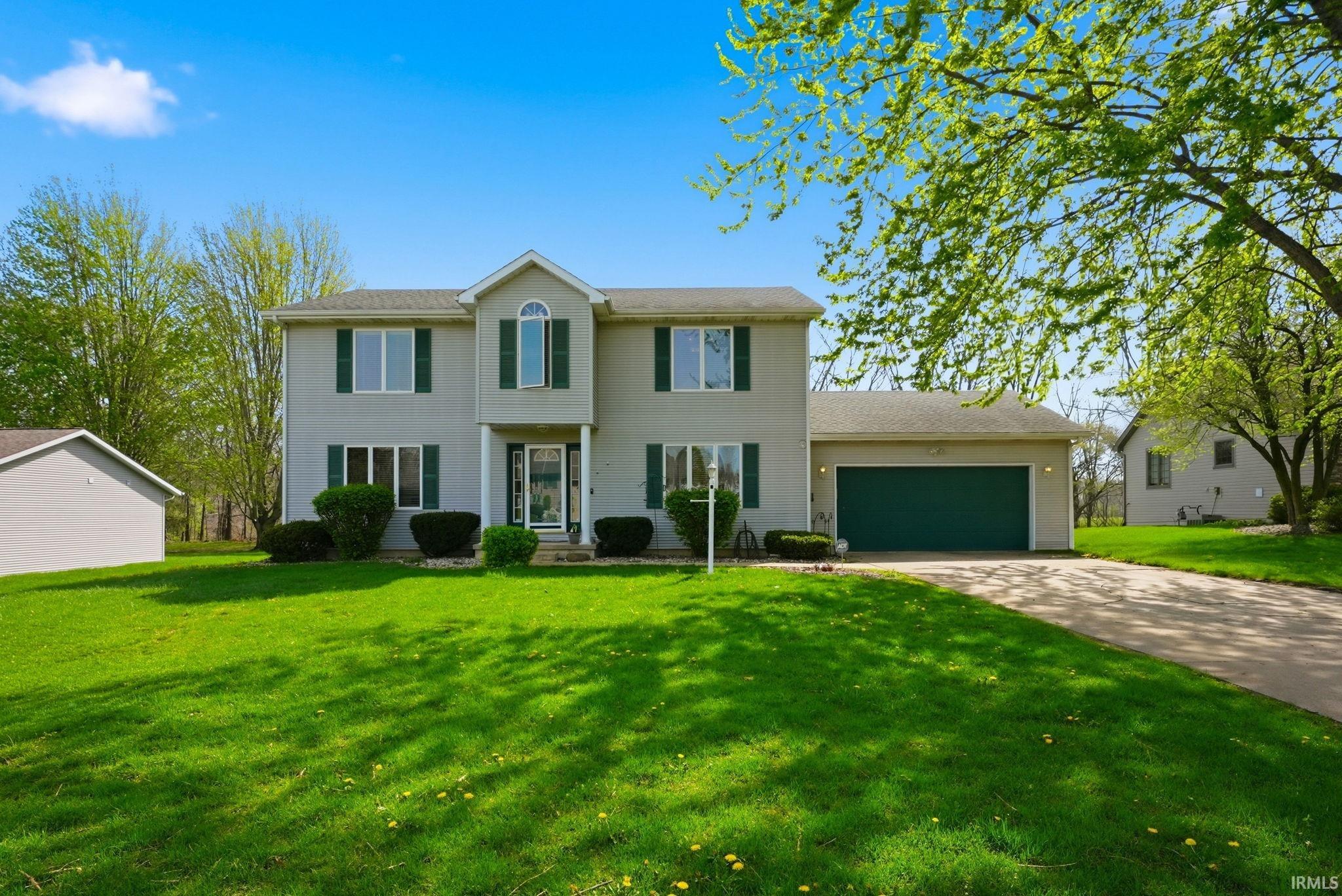 Two-story residence featuring a light gray exterior with dark green shutters and garage door