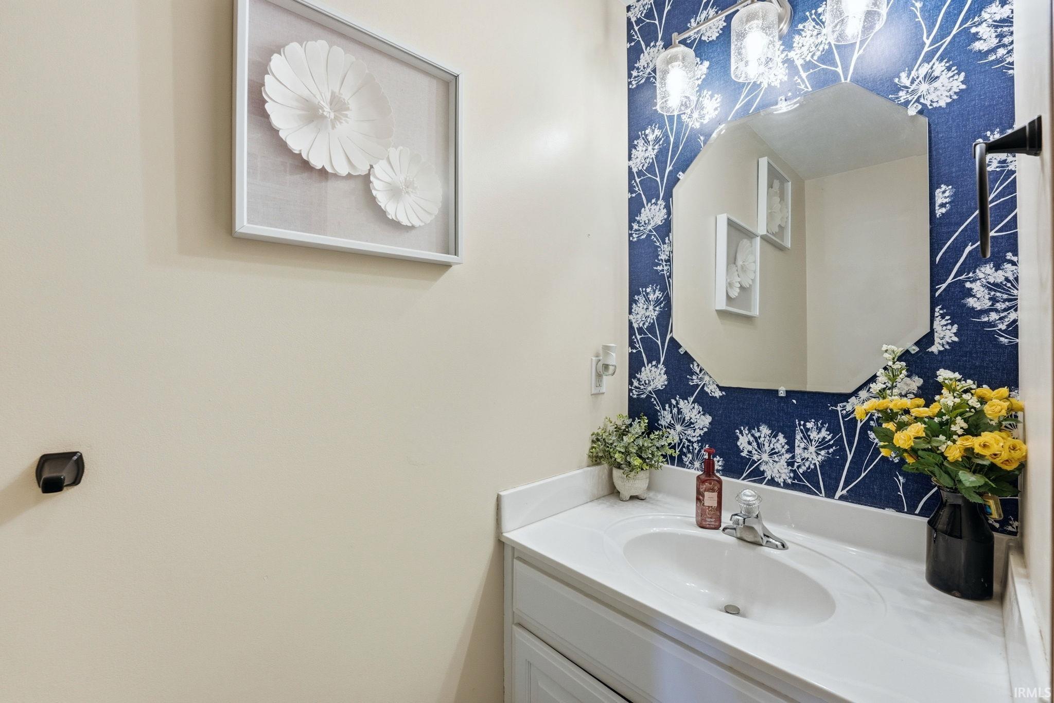 Vanity with an integrated sink and white countertop, set against a wall with blue and white patterned wallcovering