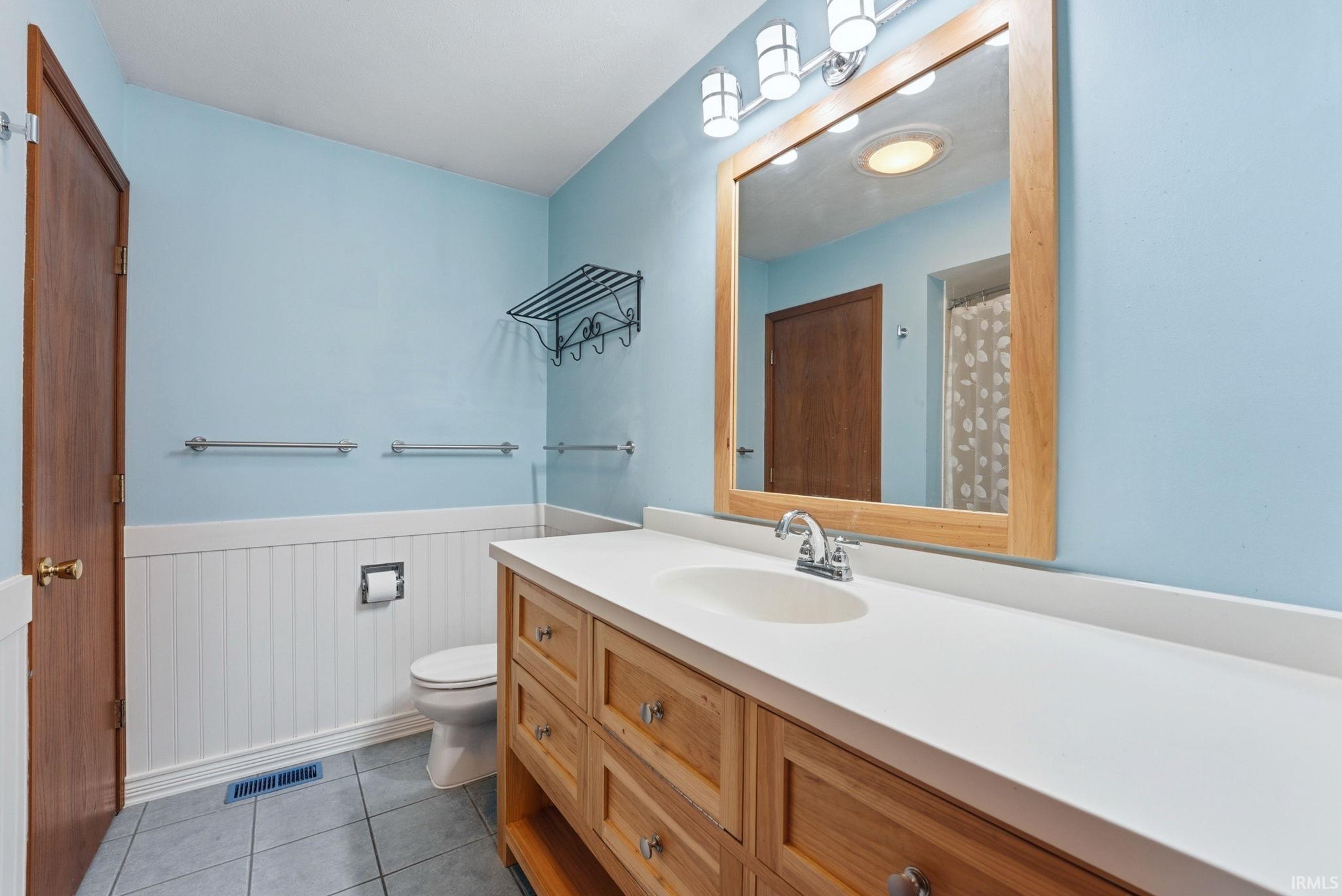 Bathroom featuring a wood-finish vanity with a white countertop and integrated sink