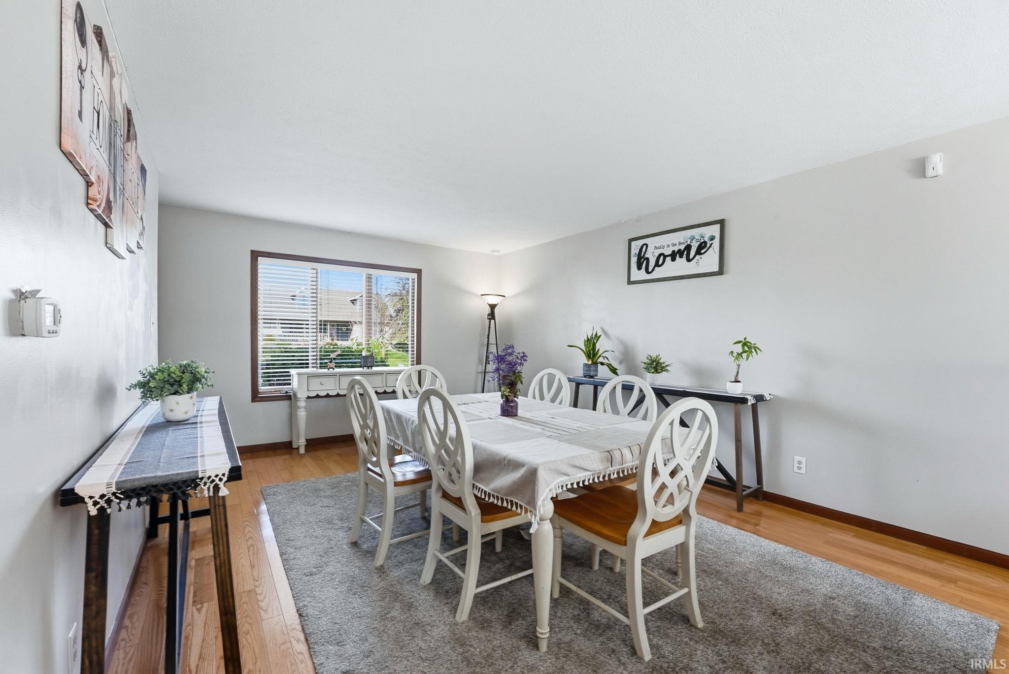 Dining area featuring a large window with blinds, light gray wall paint, and wood-finish flooring