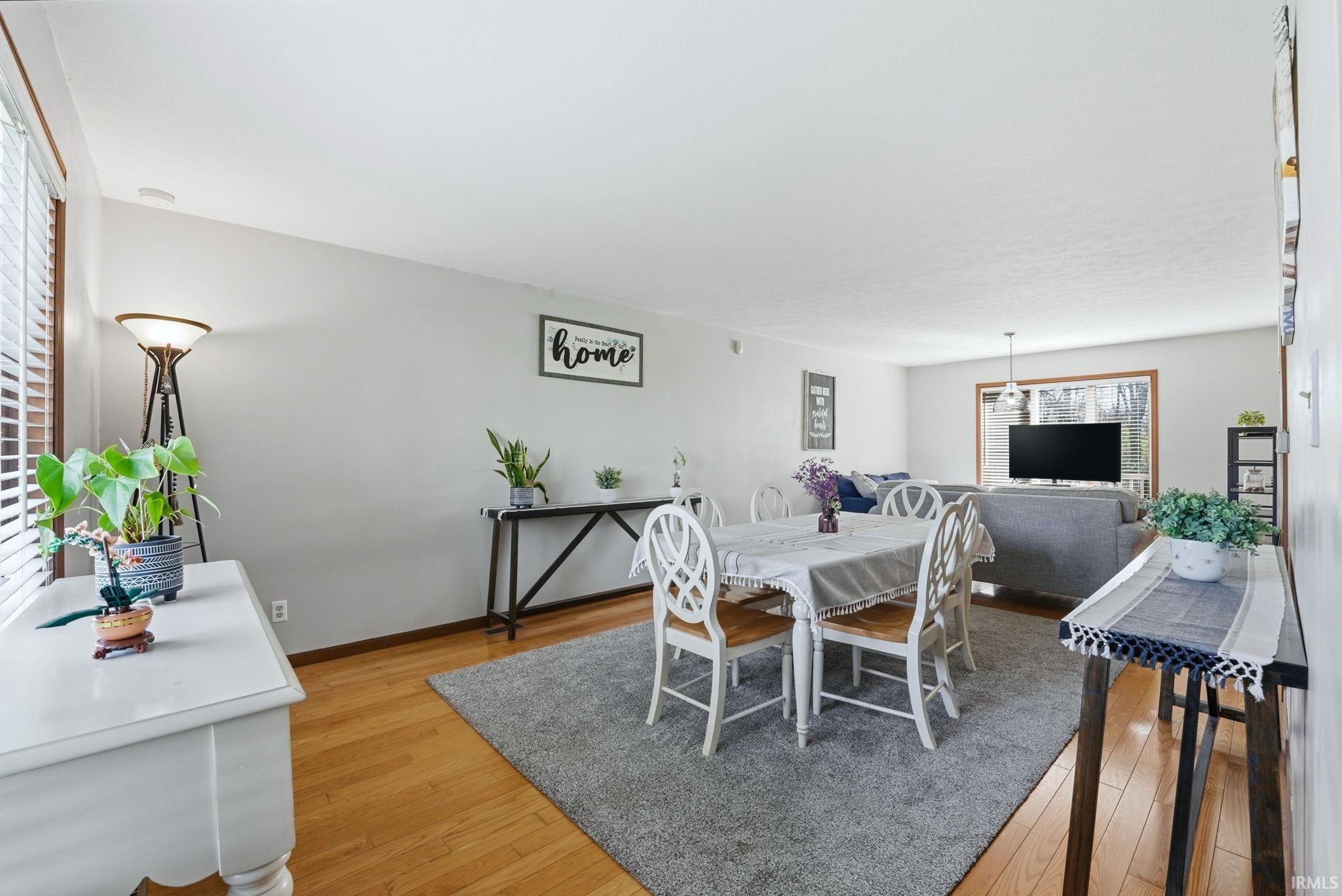 Bright living area featuring wood-finish flooring, light grey walls, and ample natural light from large windows