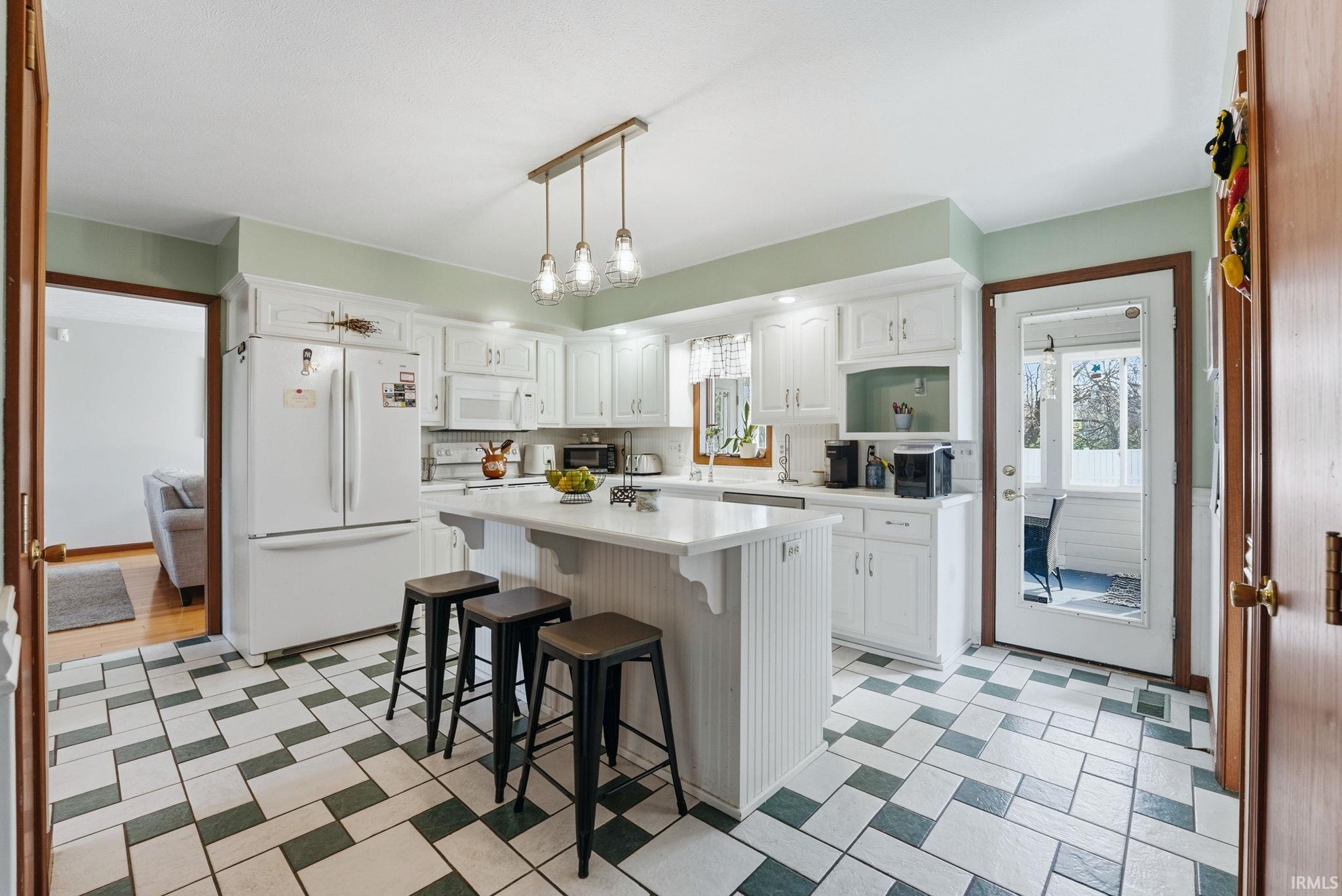 Kitchen featuring white cabinetry, a central island with countertop, a tile floor with a geometric pattern, and a full-light door