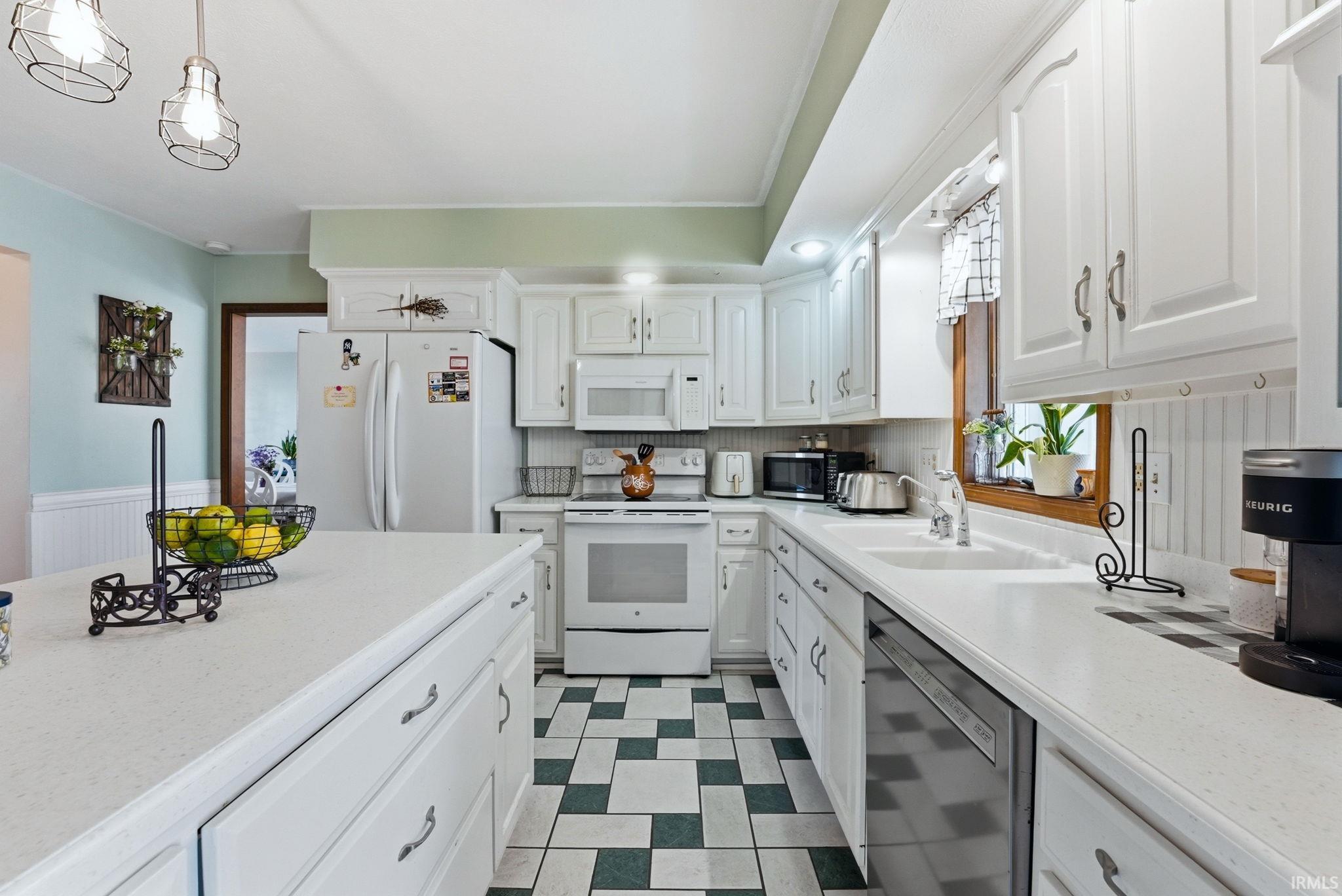 Kitchen featuring white cabinetry with brushed nickel hardware, white countertops, and a white appliance suite