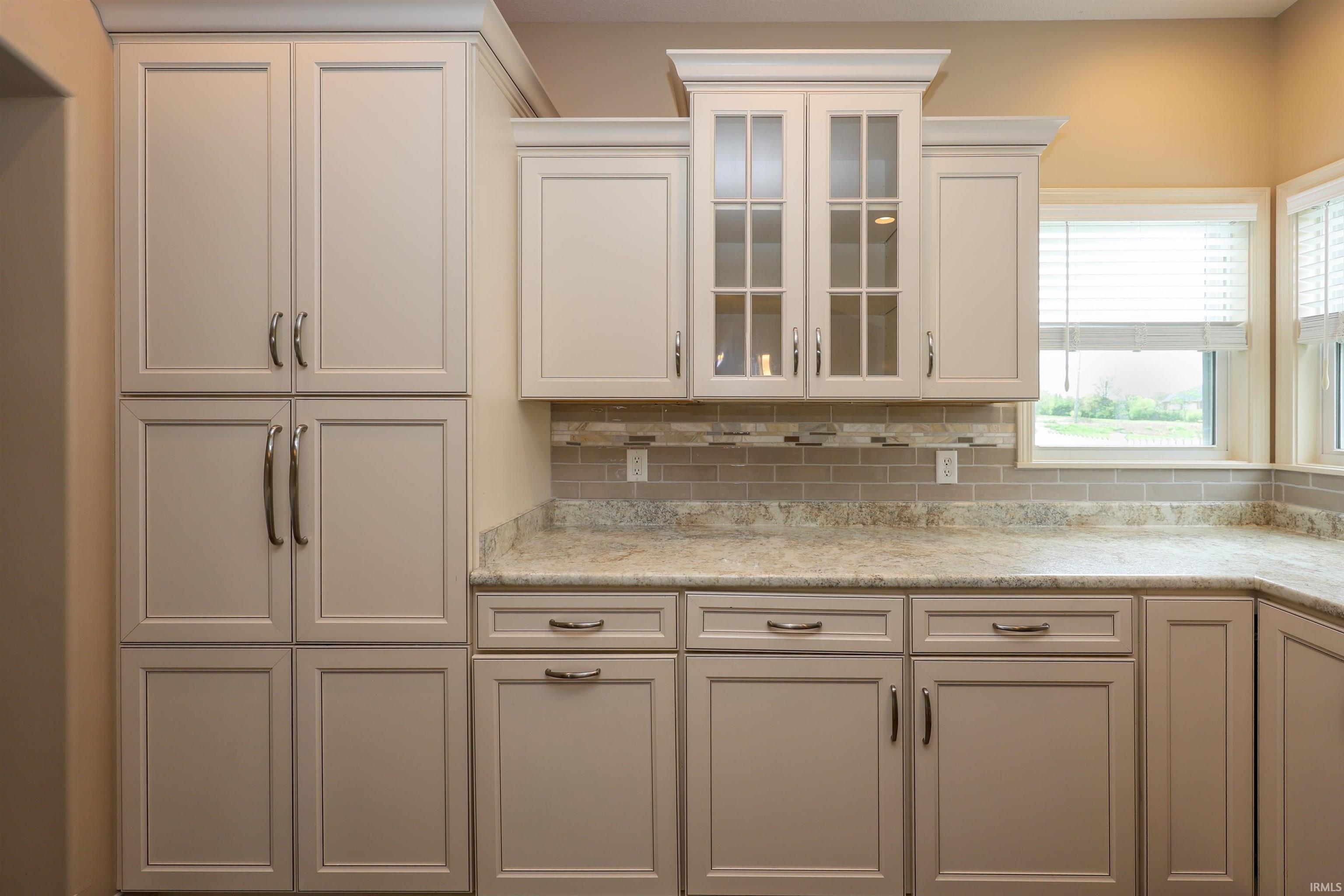 Kitchen cabinetry featuring crown molding, glass-front upper cabinets, and brushed nickel hardware