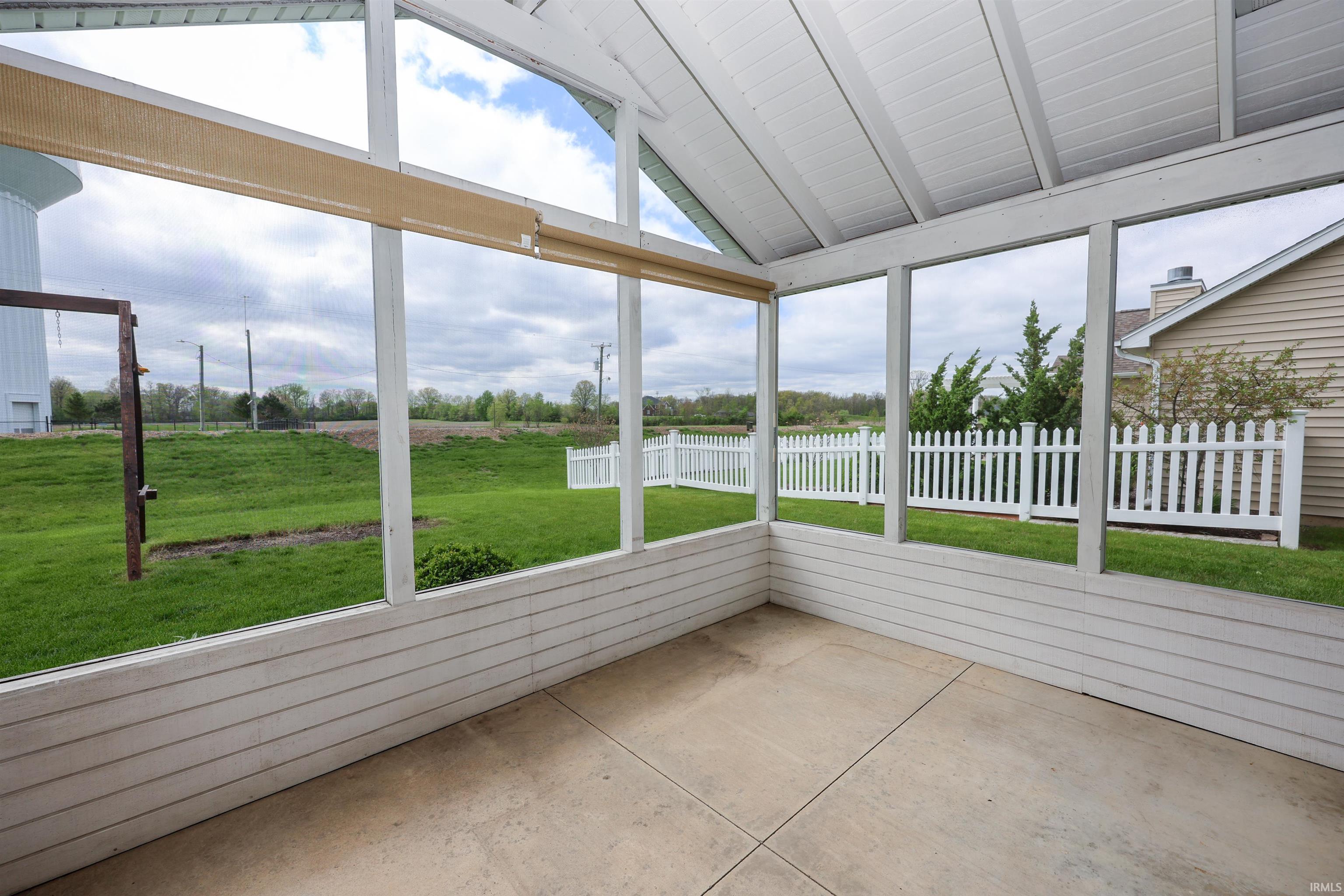 Screened-in porch featuring a vaulted ceiling and concrete flooring