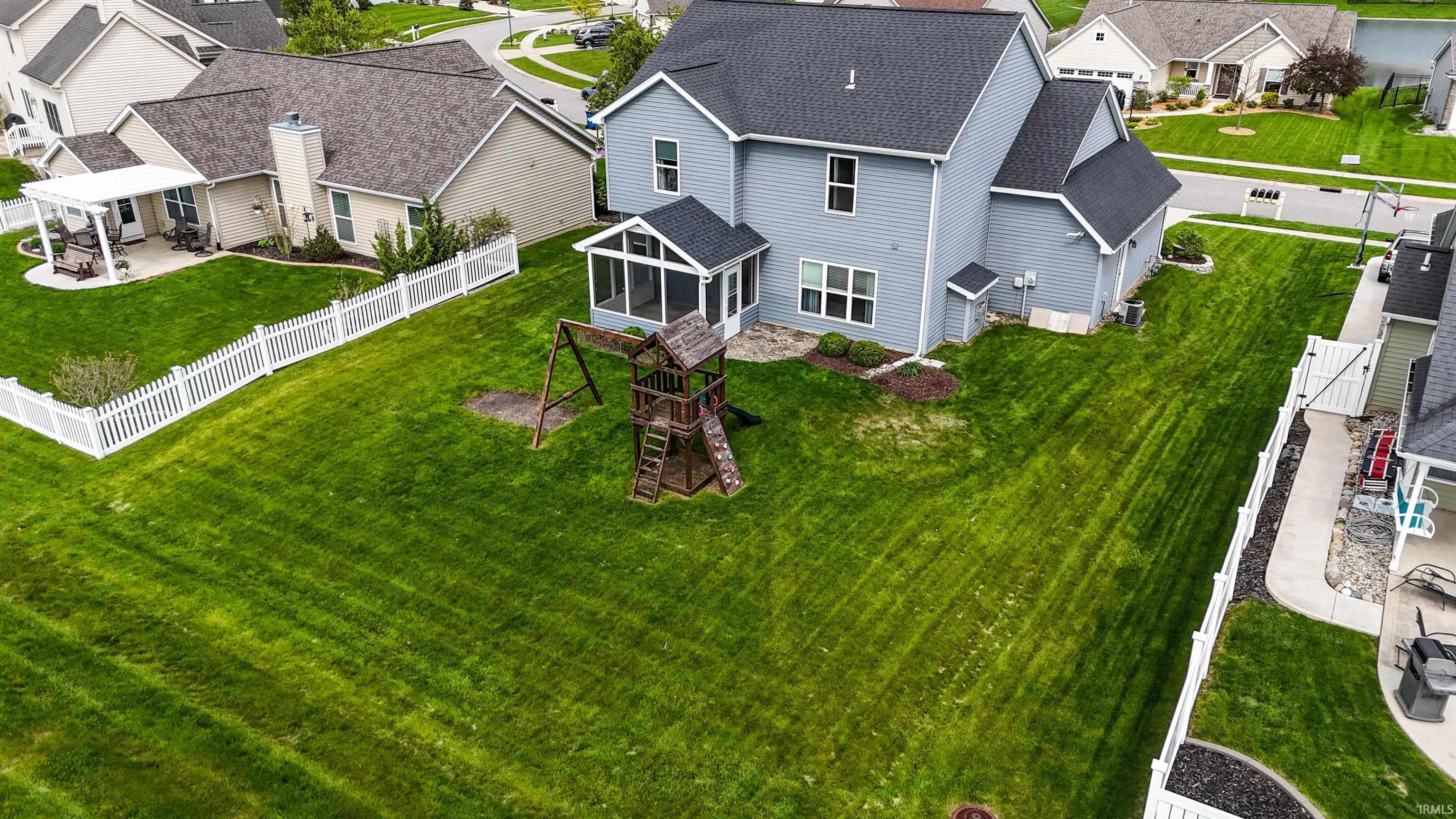 Expansive fenced backyard featuring a screened porch, a stone patio, and a decorative play structure