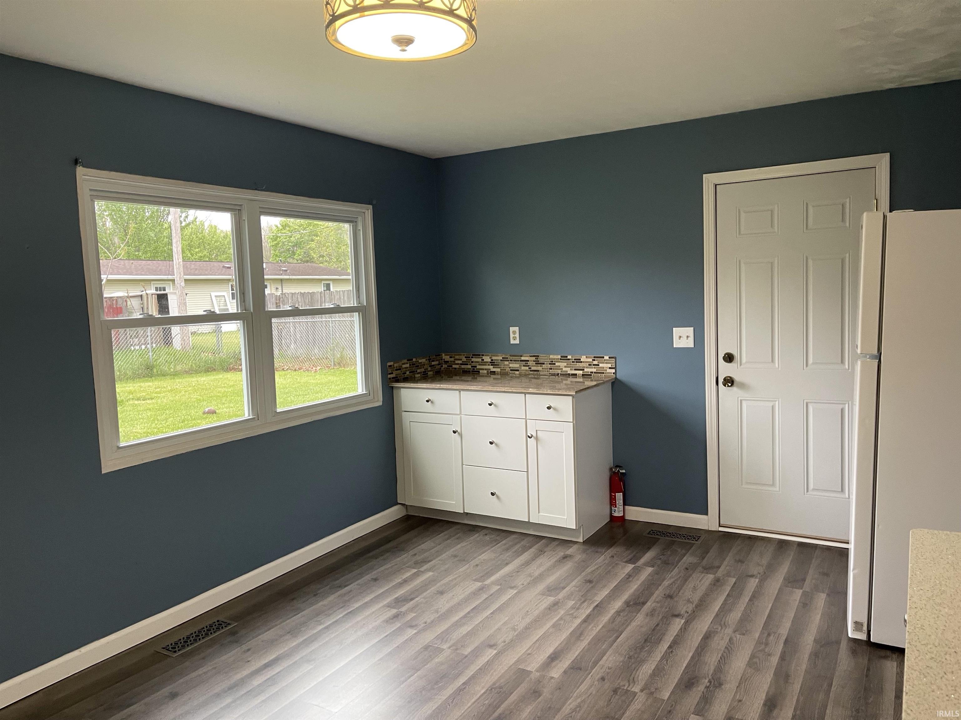 Spacious interior with vibrant blue walls, wood-finish flooring, and a large window
