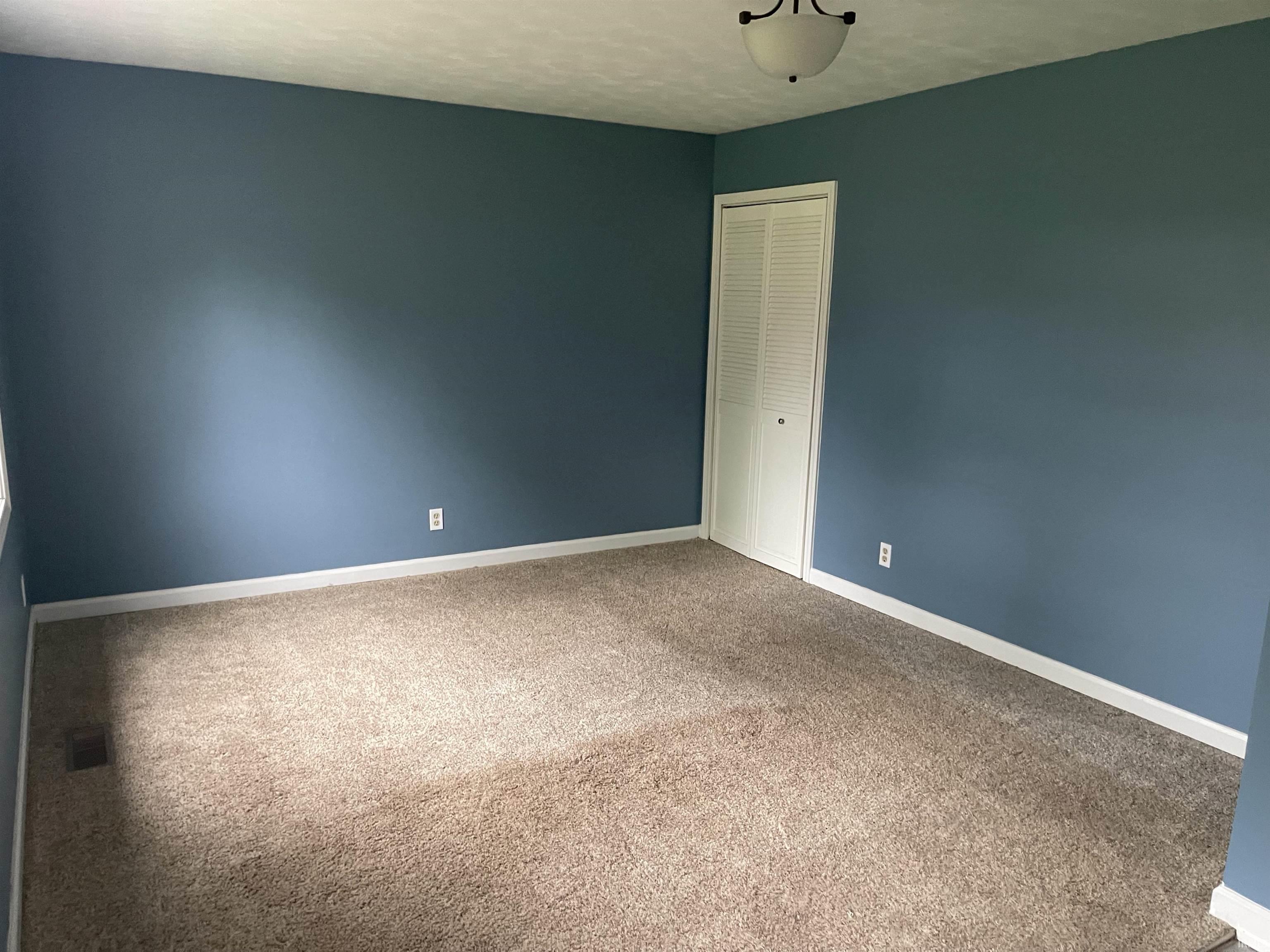 Bedroom featuring blue painted walls, white baseboards, and neutral-toned carpet