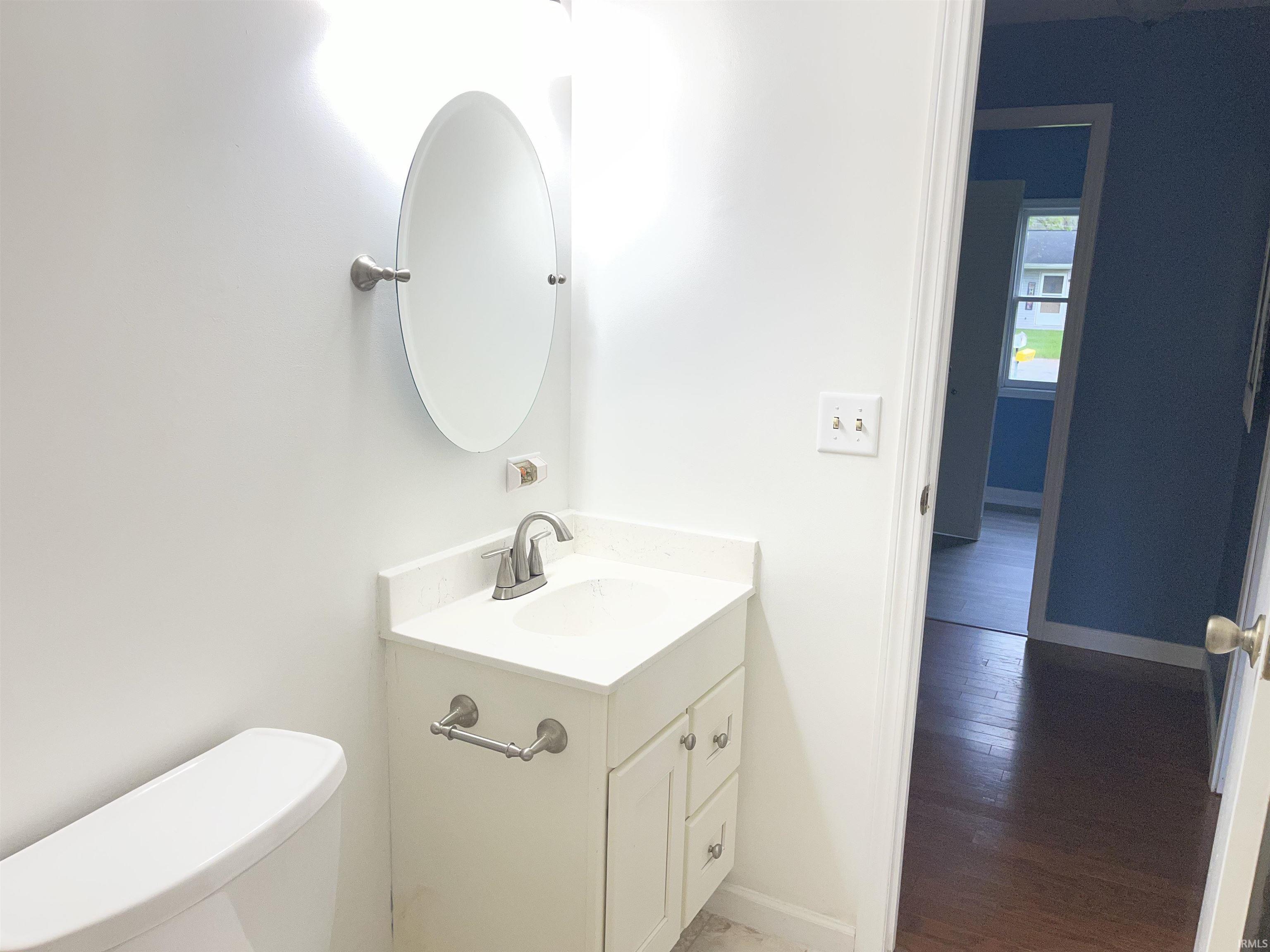 Bathroom vanity featuring a white countertop with integrated sink, brushed nickel faucet, and an oval mirror