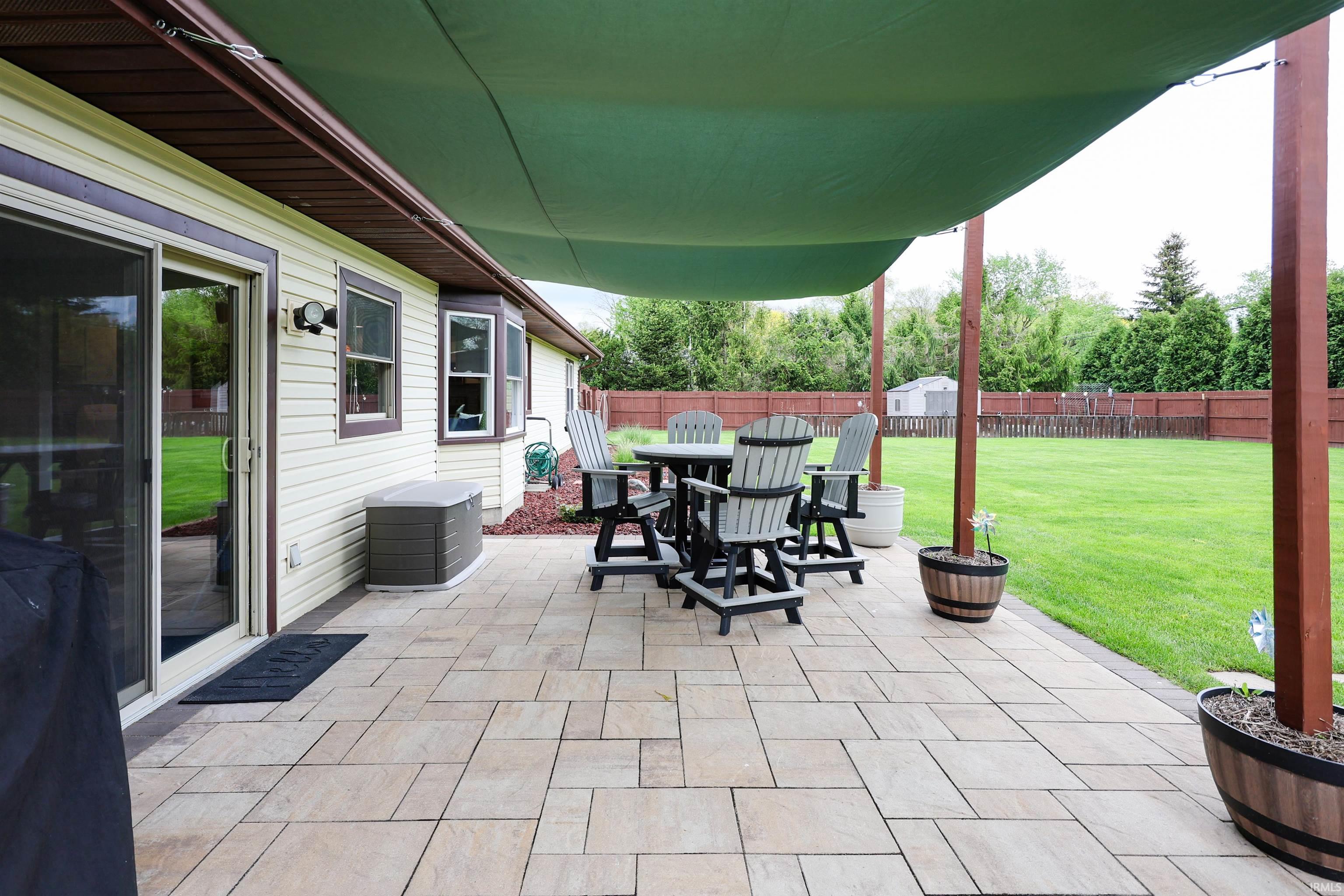 Expansive paver patio featuring a green shade sail