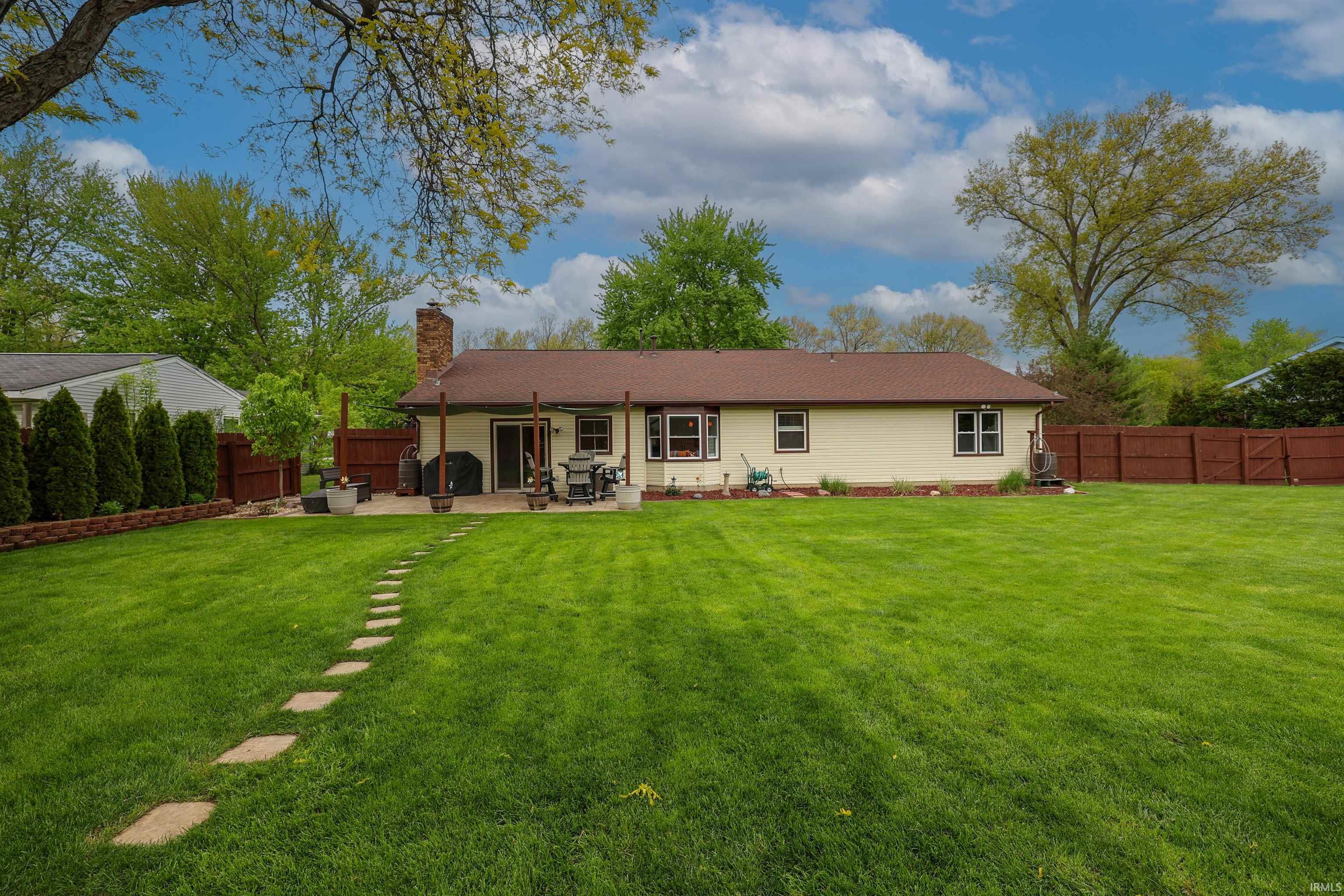 Expansive green lawn with a stepping stone pathway leading to a patio