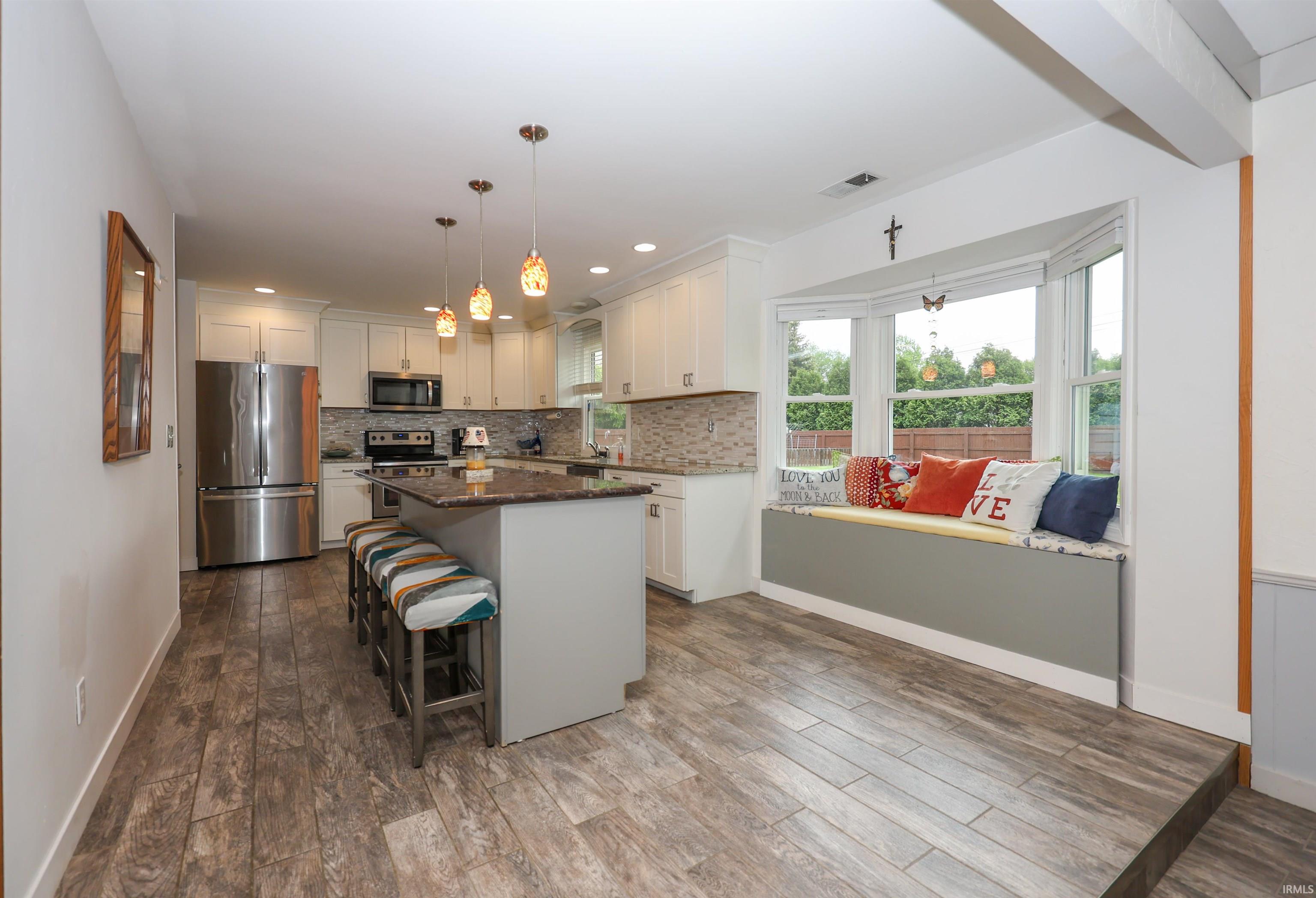 Modern kitchen featuring white cabinetry, stainless steel appliances, and a mosaic tile backsplash