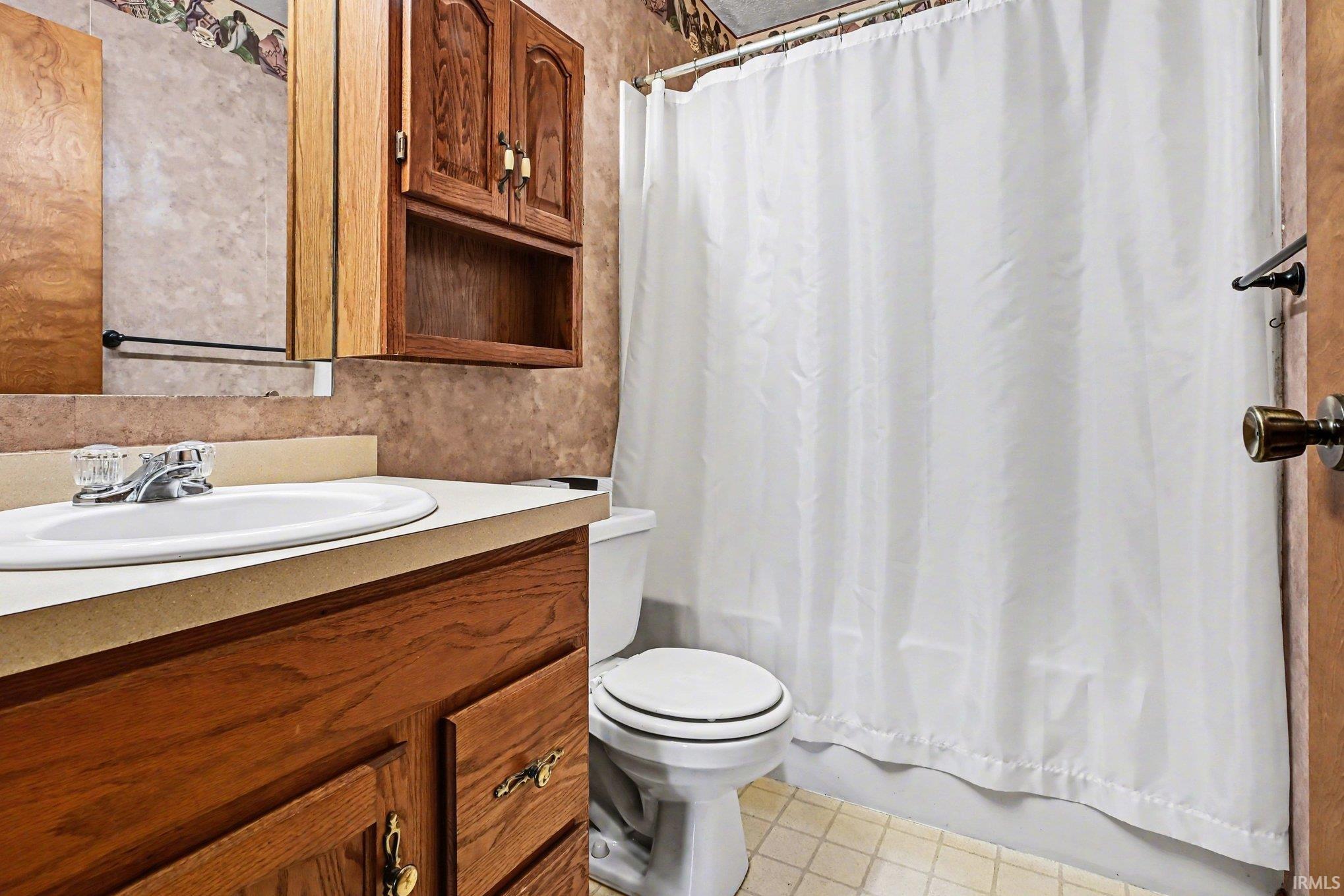 Bathroom featuring a wood-finish vanity with an integrated sink and laminate countertop