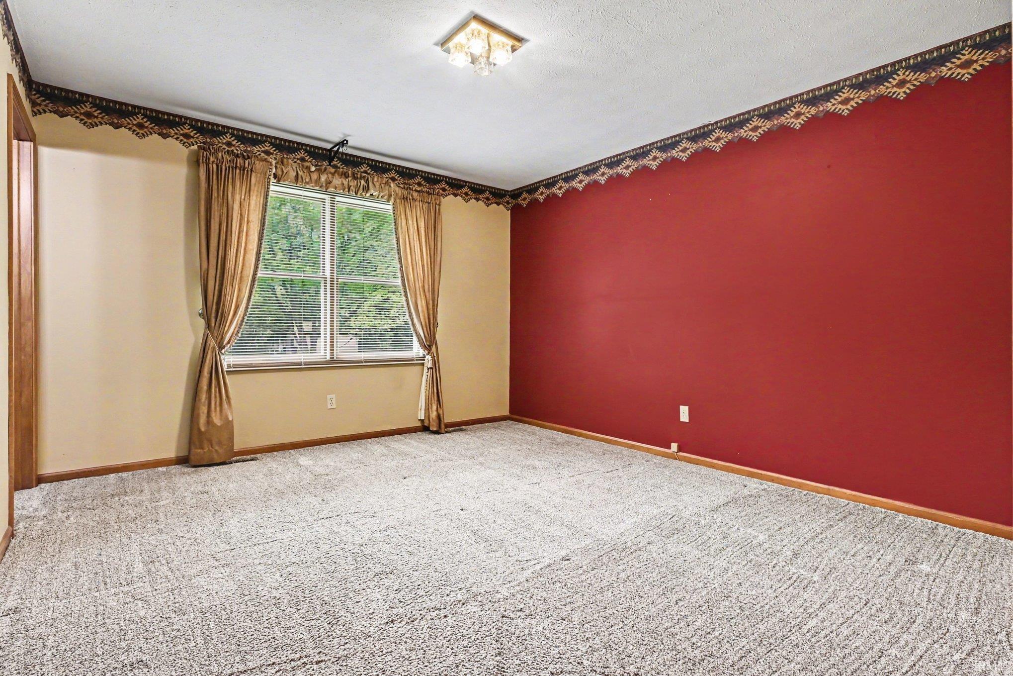 Room featuring patterned carpet flooring, a large window, and decorative wall border