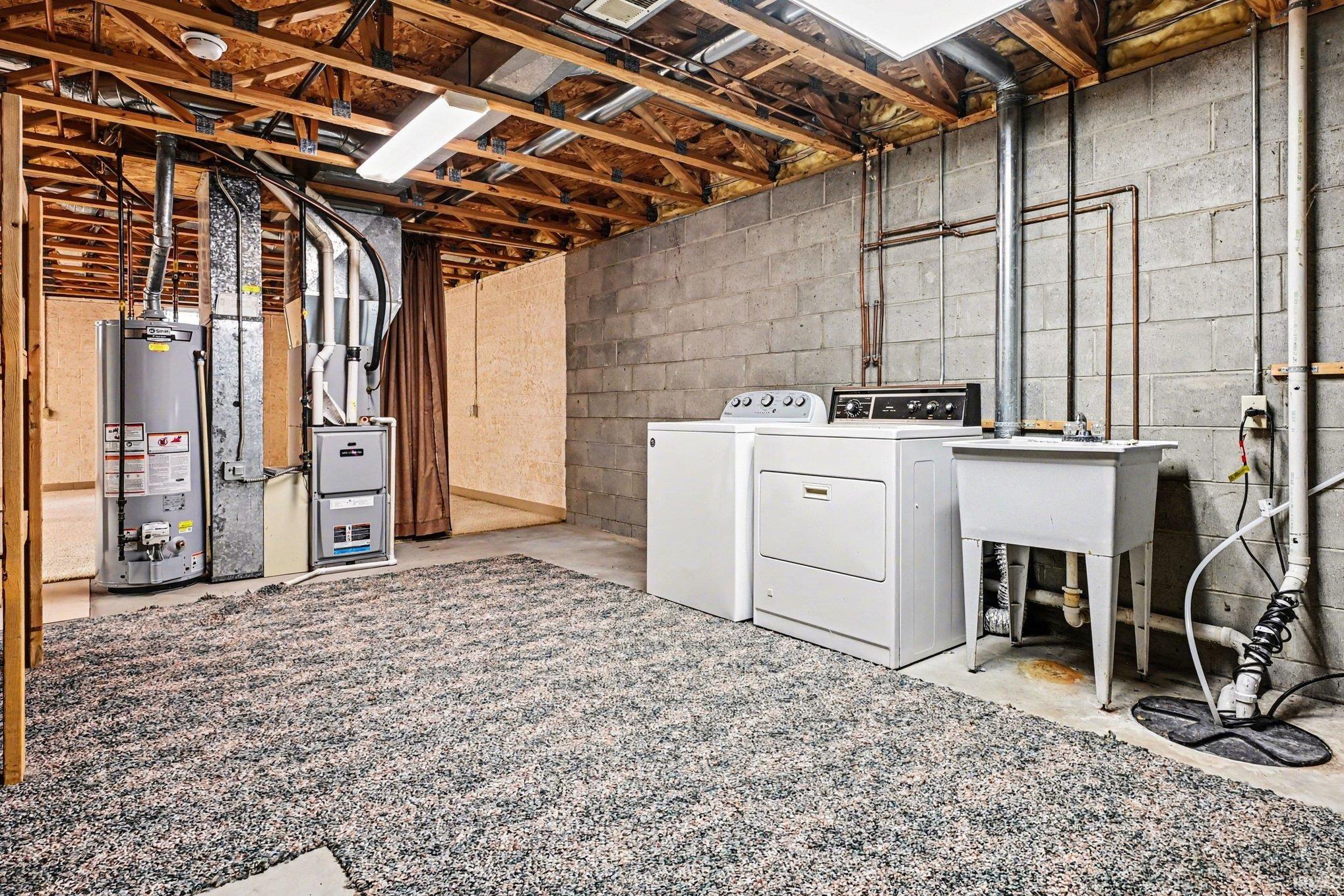 Utility area featuring a washer and dryer, laundry sink, water heater, and furnace