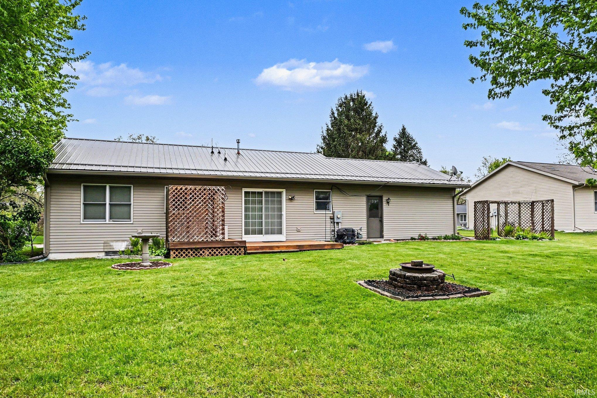 Expansive rear yard featuring a central stone fire pit