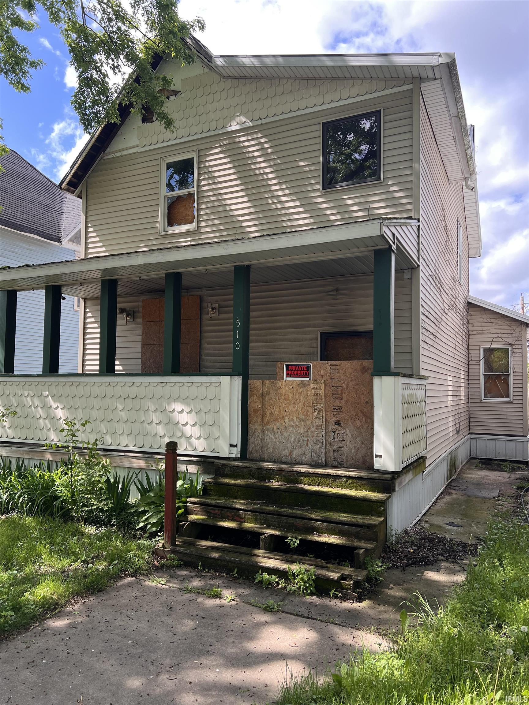 Two-story property featuring horizontal siding and decorative scallop-edge siding on the upper gable