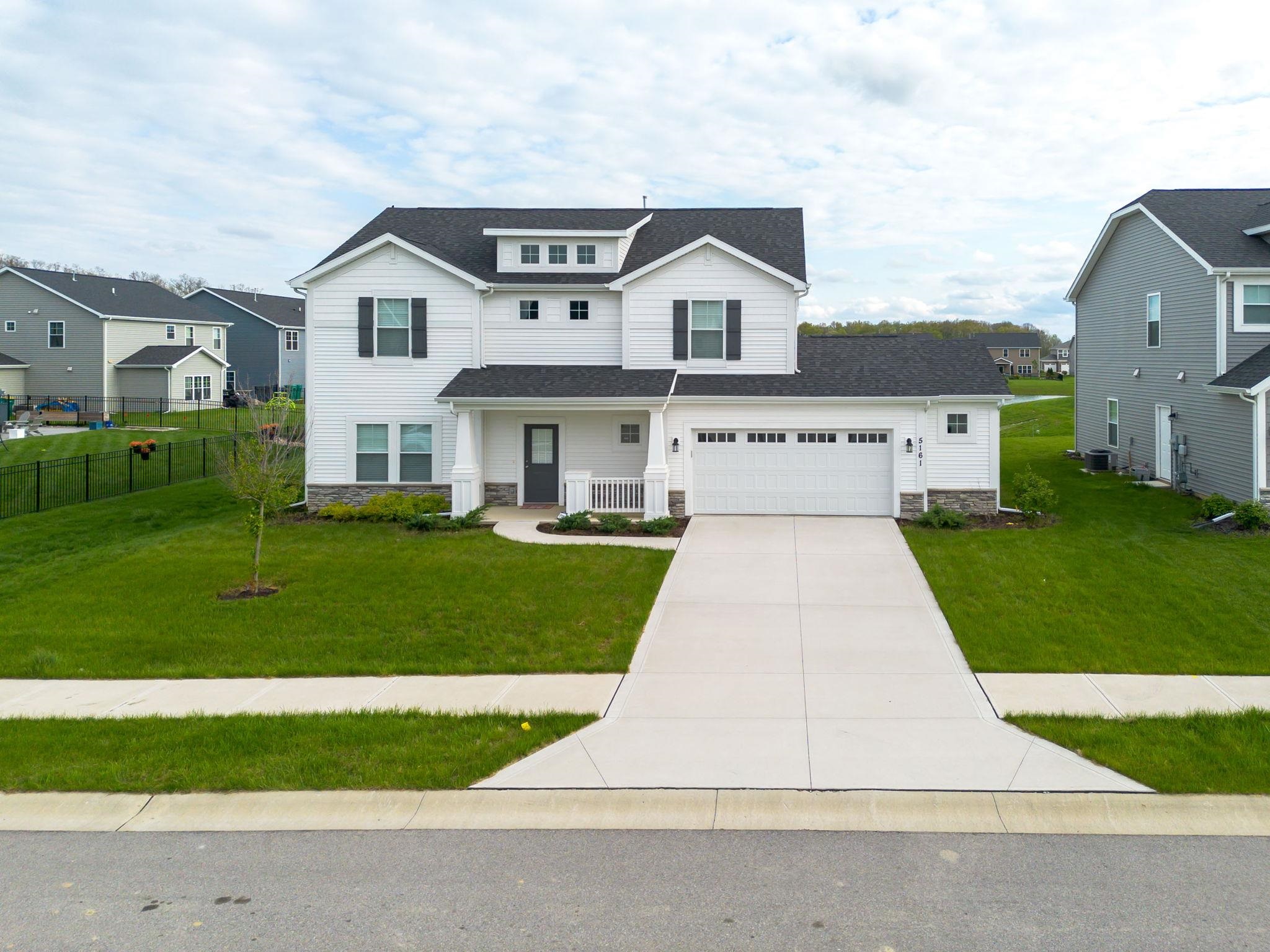 Contemporary two-story residence with white siding and dark gray shutters