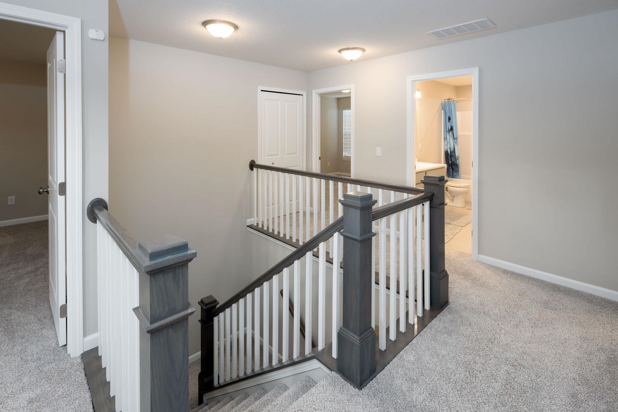 Upper-level landing featuring a staircase with painted balusters, a built-in linen closet, and a recessed ceiling light