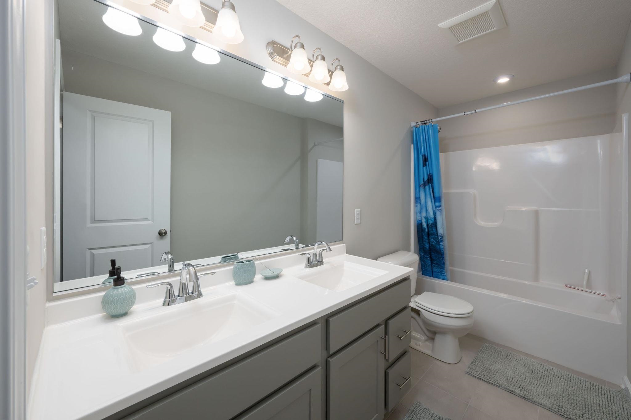 Bathroom featuring a dual vanity with a white countertop, two undermount sinks, and chrome faucets