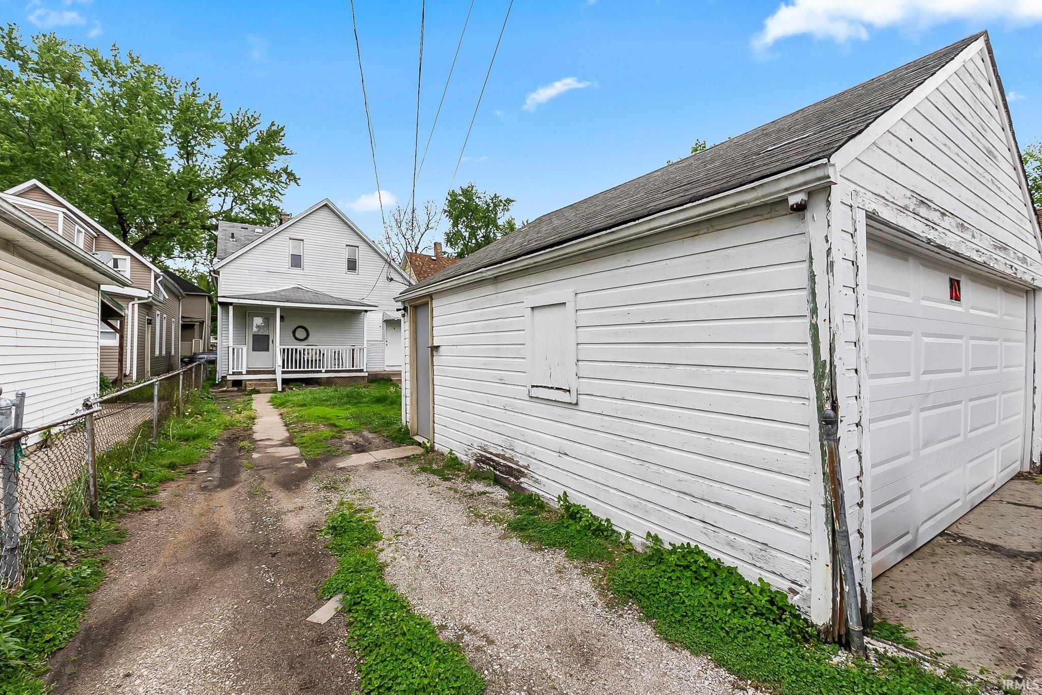 Detached garage structure featuring white siding and a panel garage door