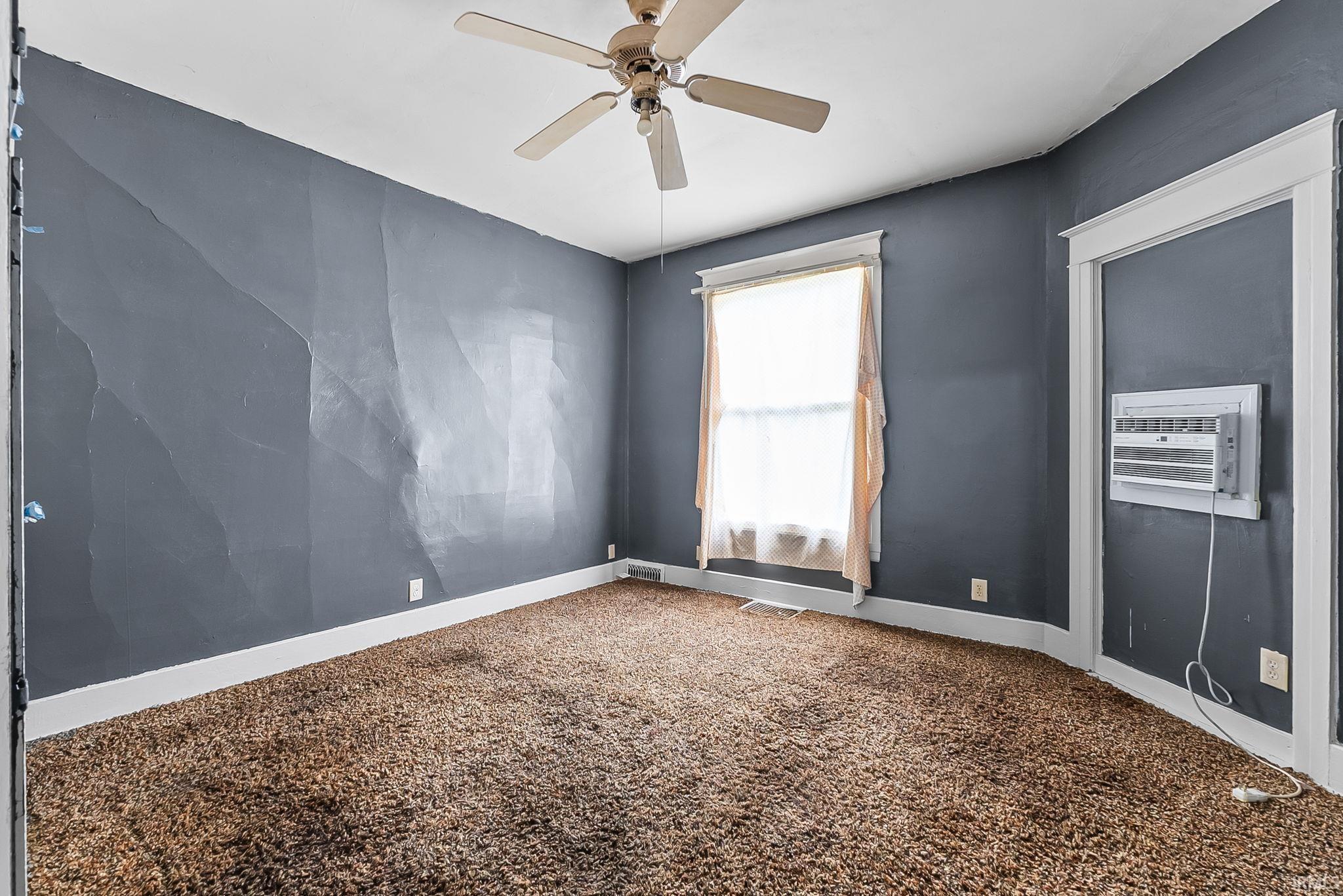 Room featuring textured gray walls, brown carpet, and white trim