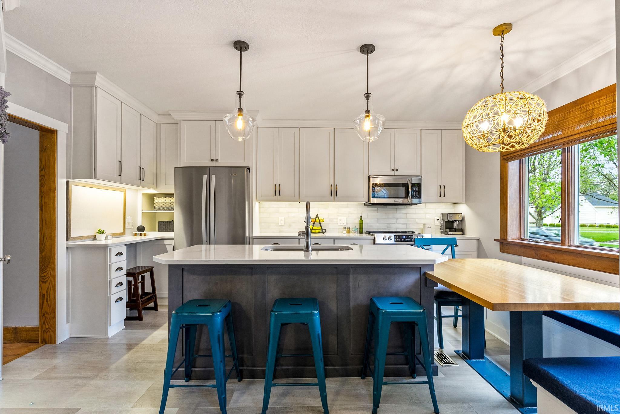 Central kitchen island with a light-toned countertop and dark base, surrounded by light gray cabinetry