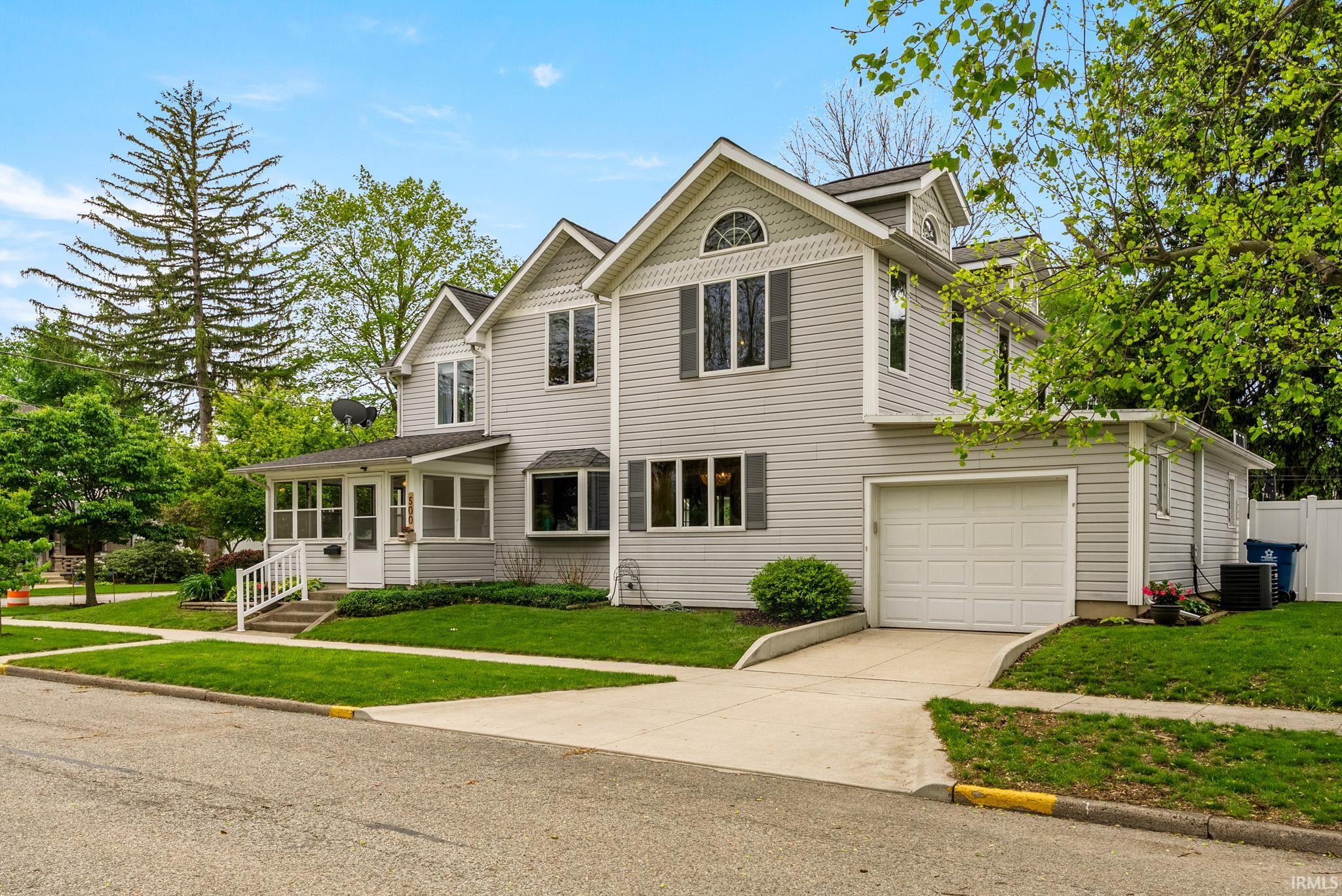 Two-story residence featuring light gray siding with white trim accents and dark gray window shutters