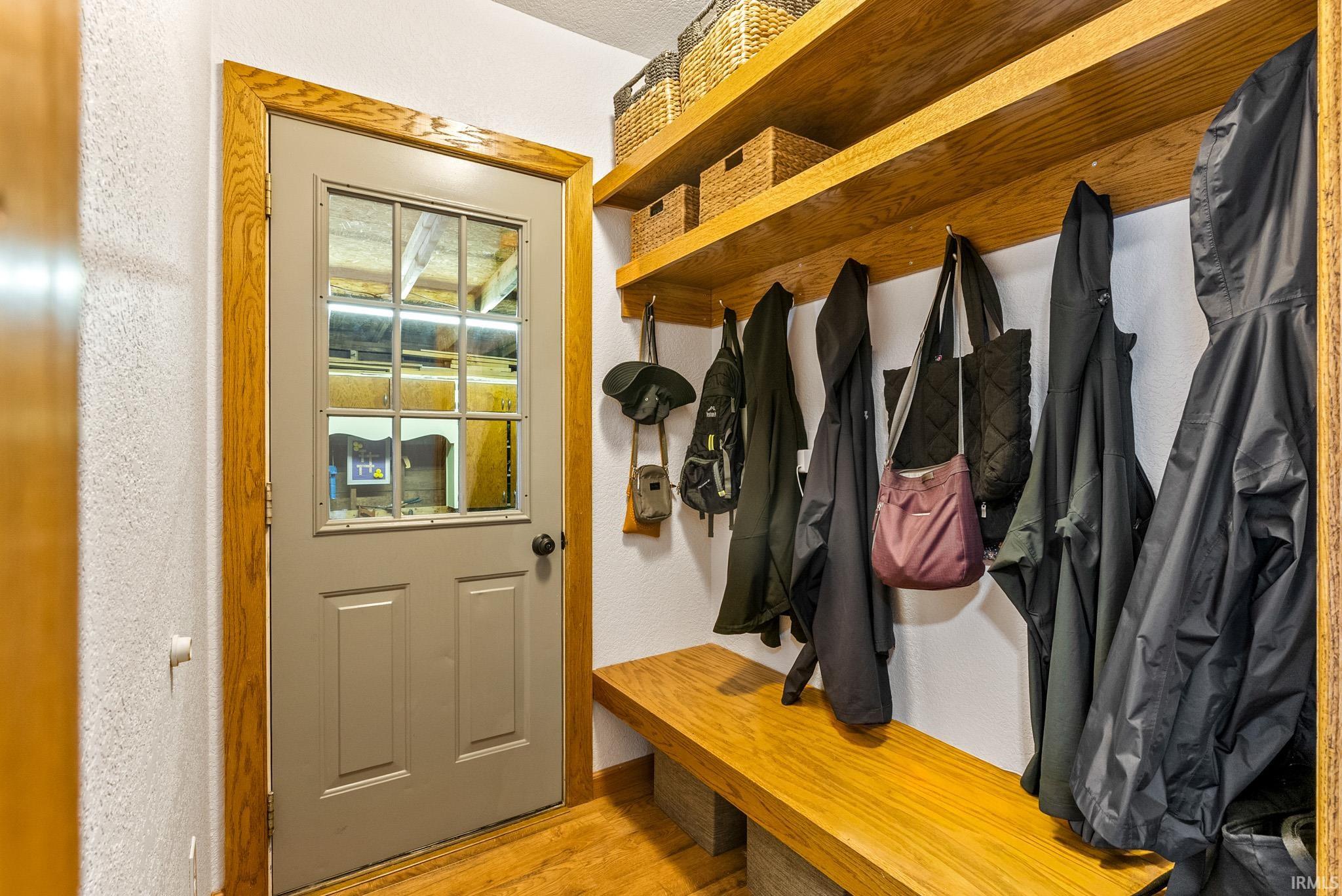 Entryway featuring a paneled door with windowpanes, wood-finish flooring, wood trim, built-in wooden shelving, and a built-in wooden bench