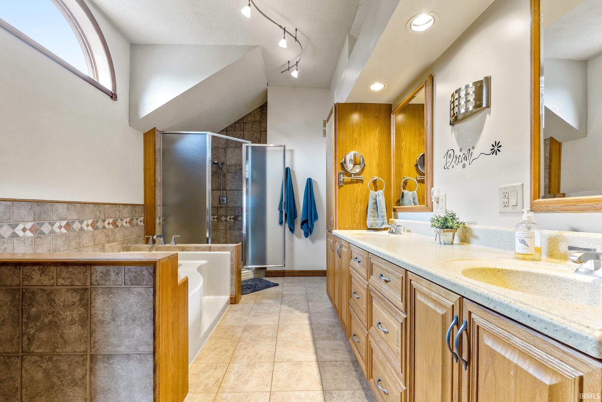 Spacious bathroom featuring a dual vanity with light-colored countertops, wood cabinetry, and integrated sinks