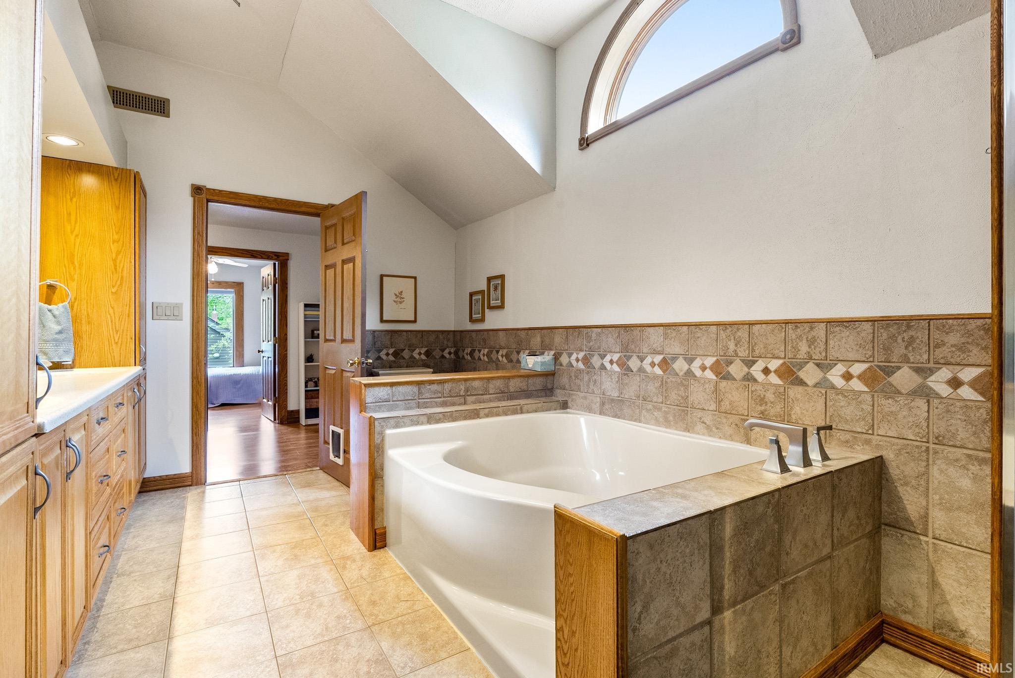 Soaking tub featuring a tiled surround with decorative accents