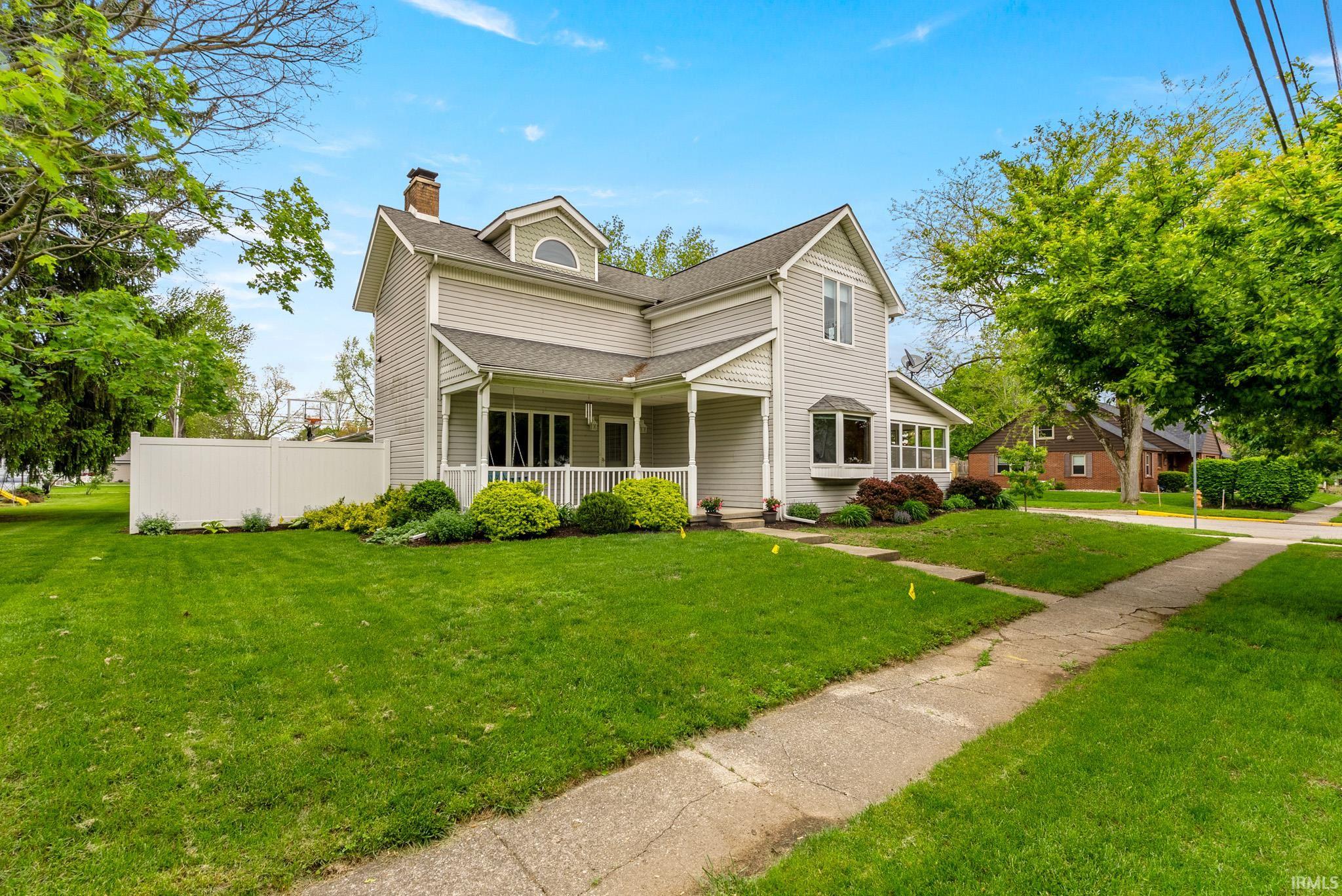 Traditional two-story residence with light gray siding and a prominent front porch with white railings