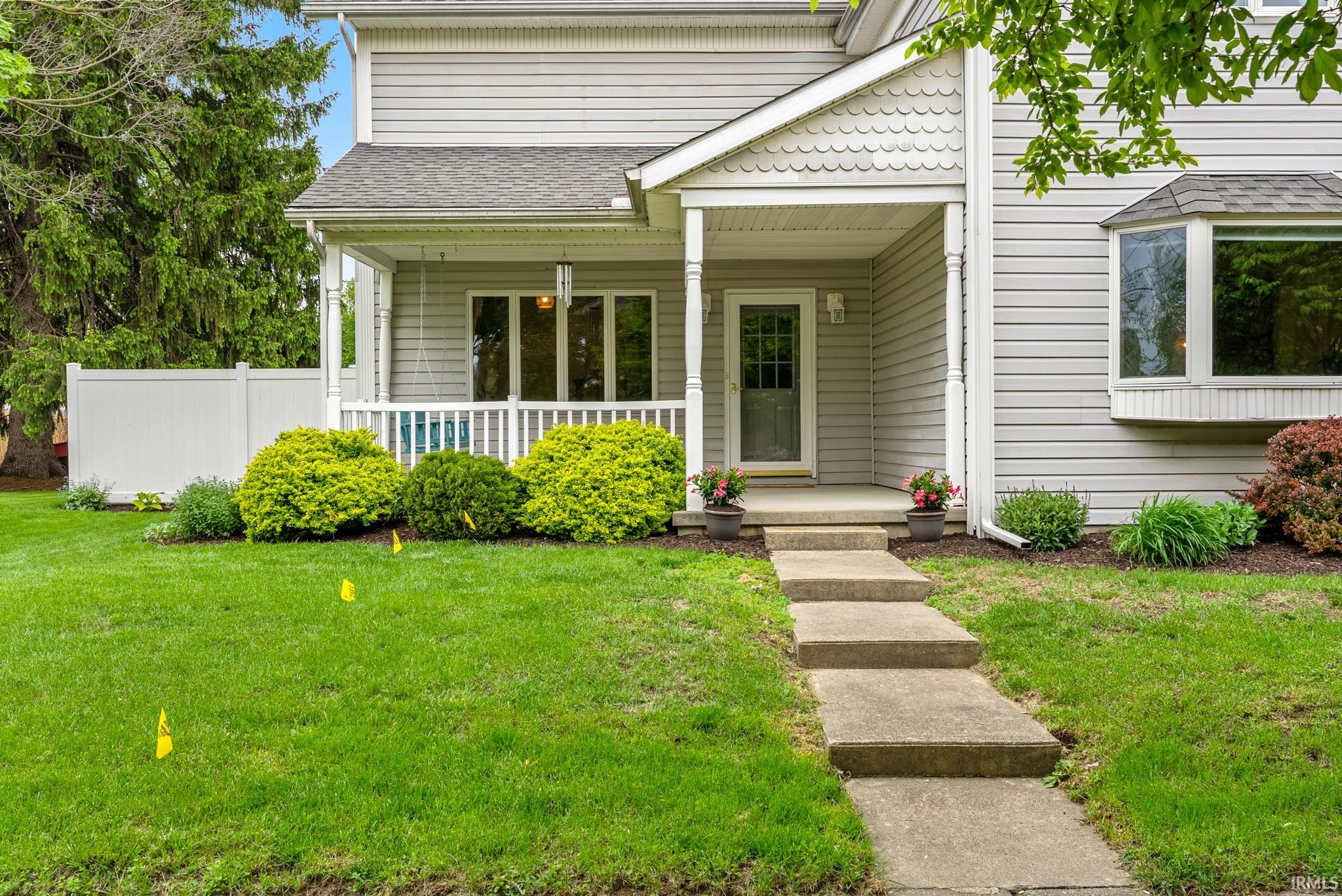 Light gray siding exterior with a shingled roof and a covered front porch featuring white railing