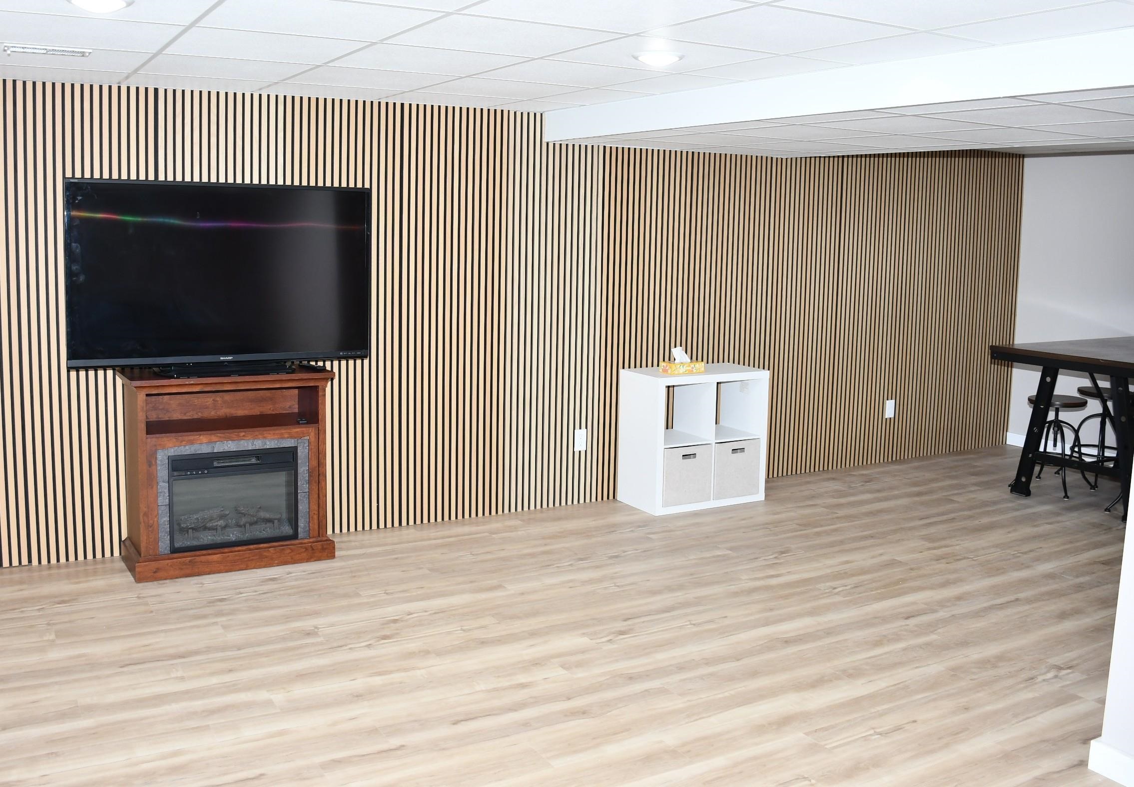 Accent wall featuring vertical wood slat paneling, complemented by wood-finish flooring and recessed ceiling lighting