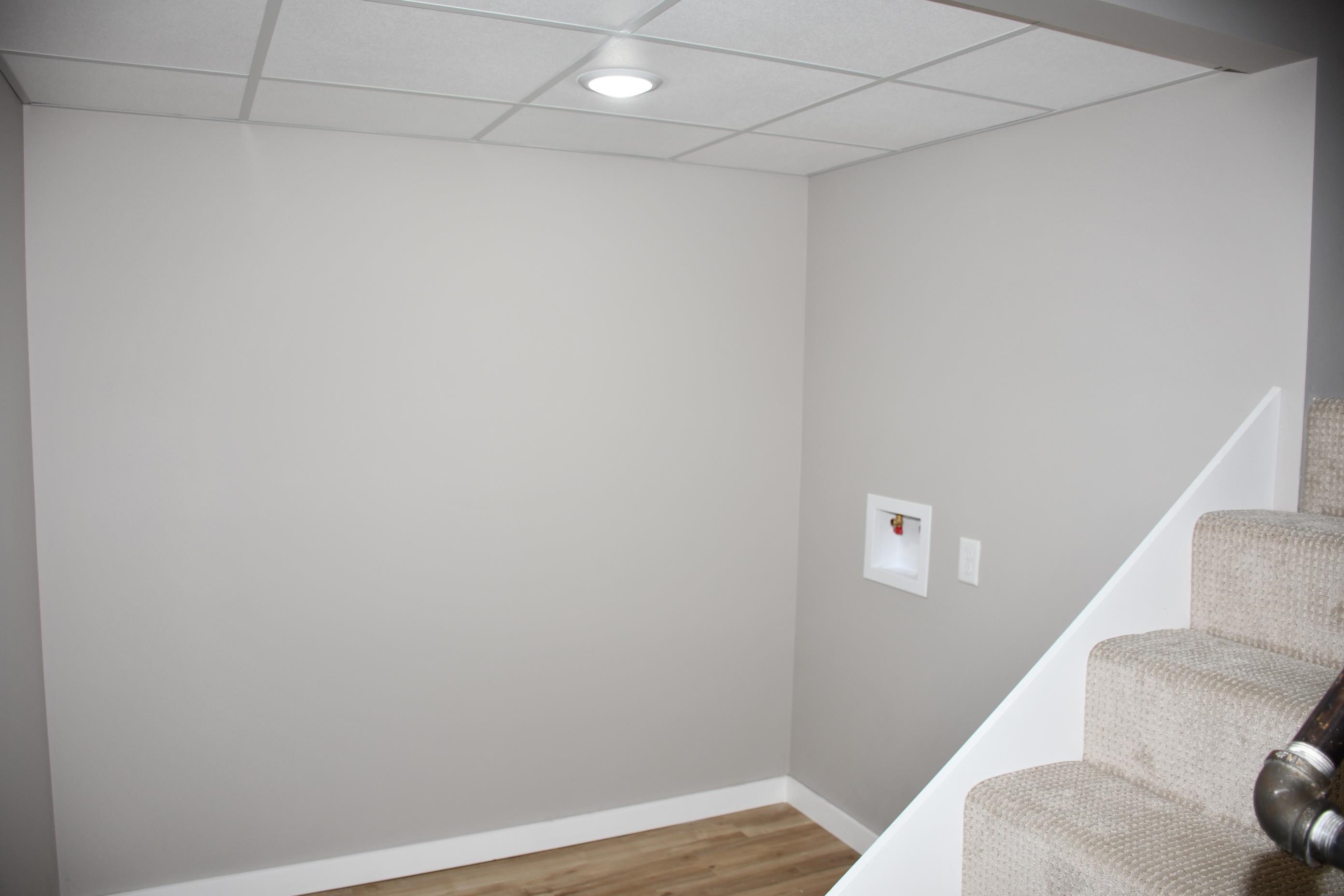 Utility area featuring light gray walls and wood-finish flooring