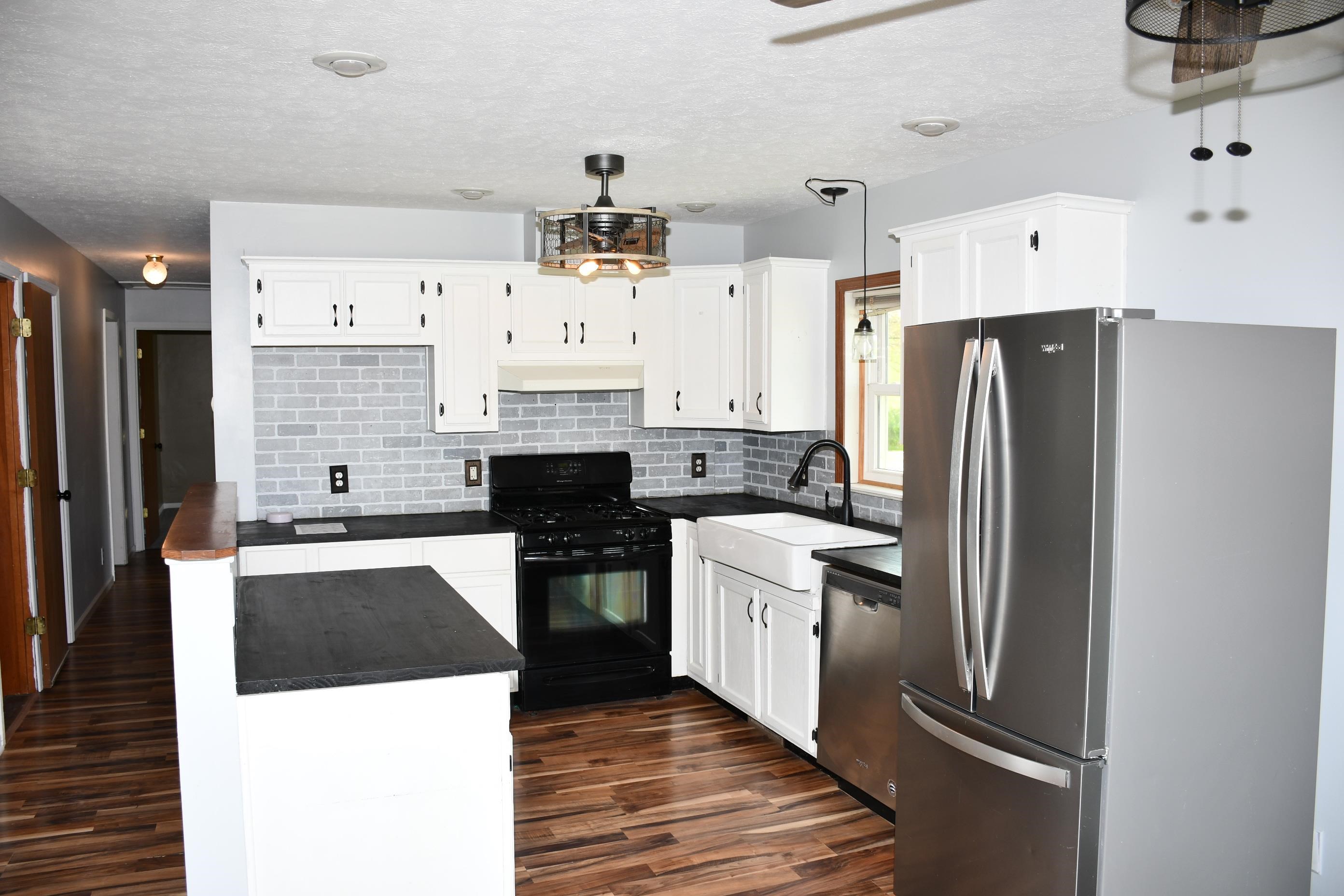 Kitchen featuring white cabinetry, a light gray subway tile backsplash, dark countertops, and wood-finish flooring