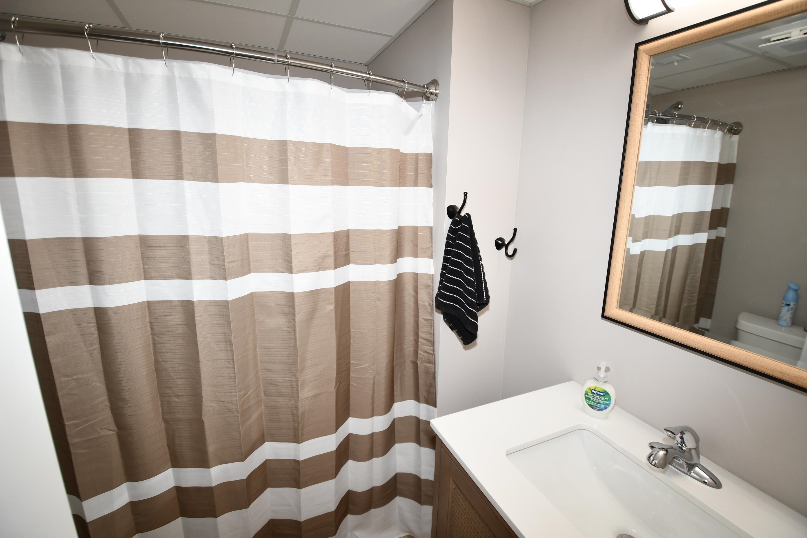 Bathroom vanity with a white countertop and integrated sink, chrome faucet, and a wall-mounted mirror featuring a wood-finish frame