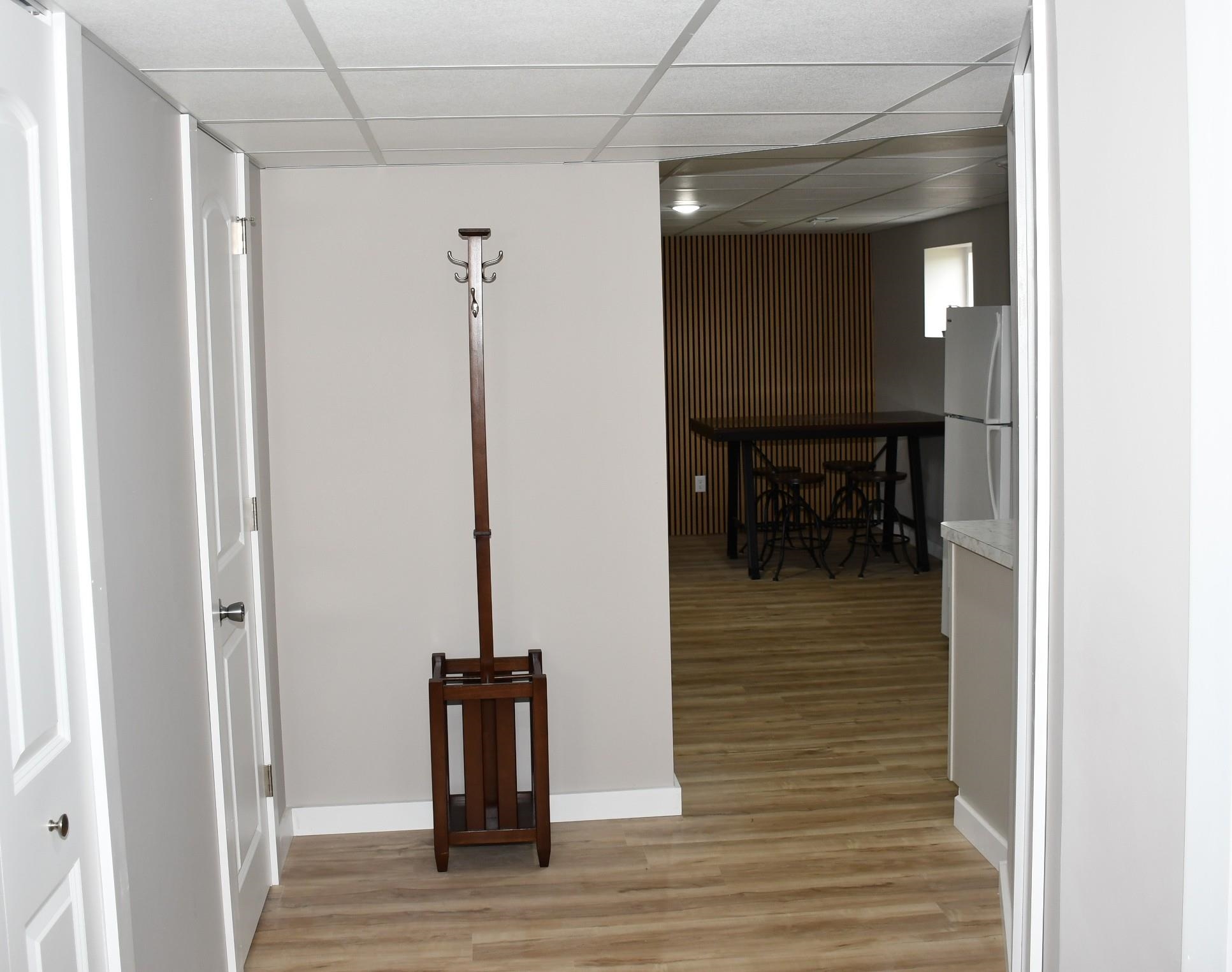 Light wood-finish flooring extending into an open concept area with a textured wood accent wall and a recessed window