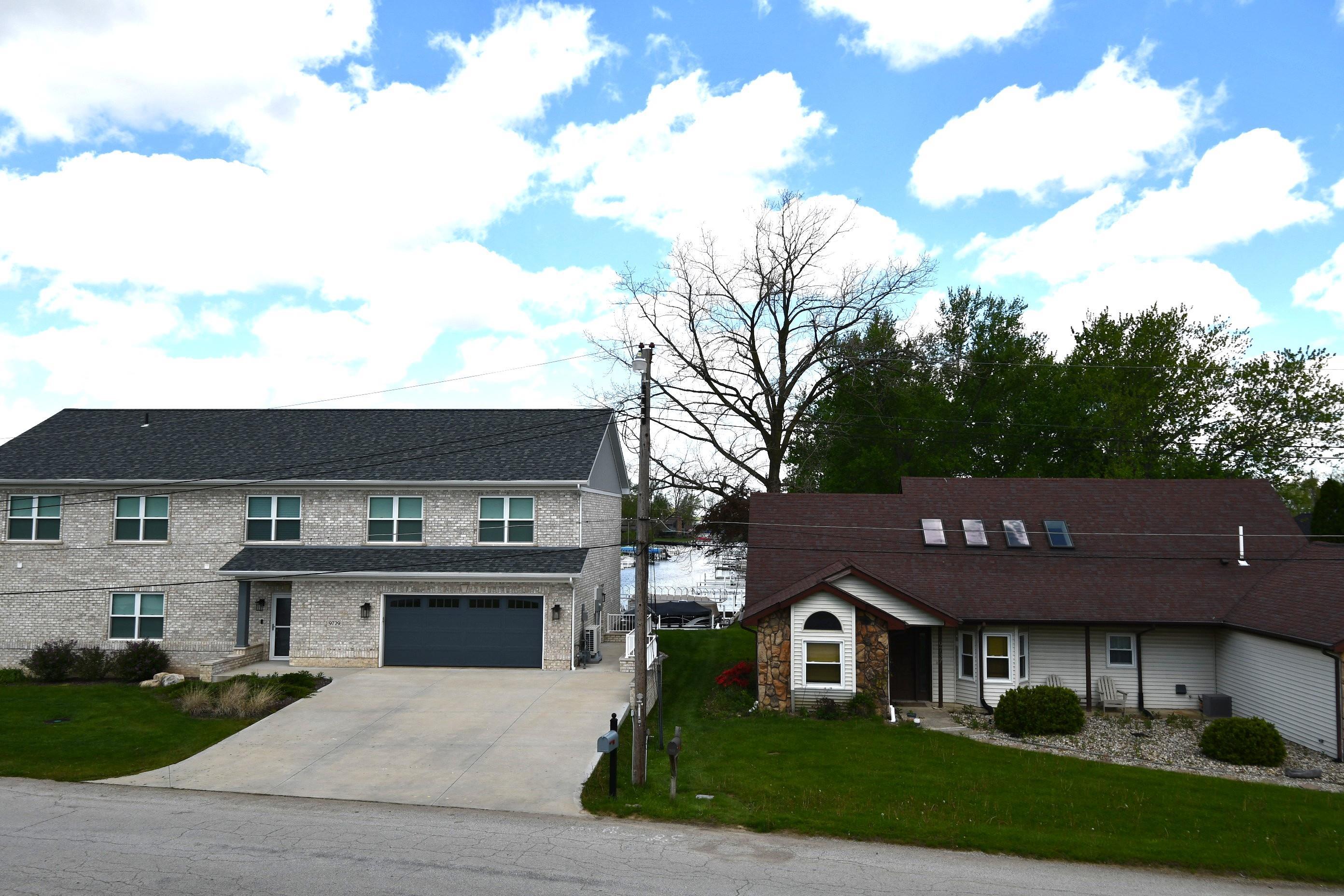 Gray brick facade with a dark gray shingle roof and an attached two-car garage