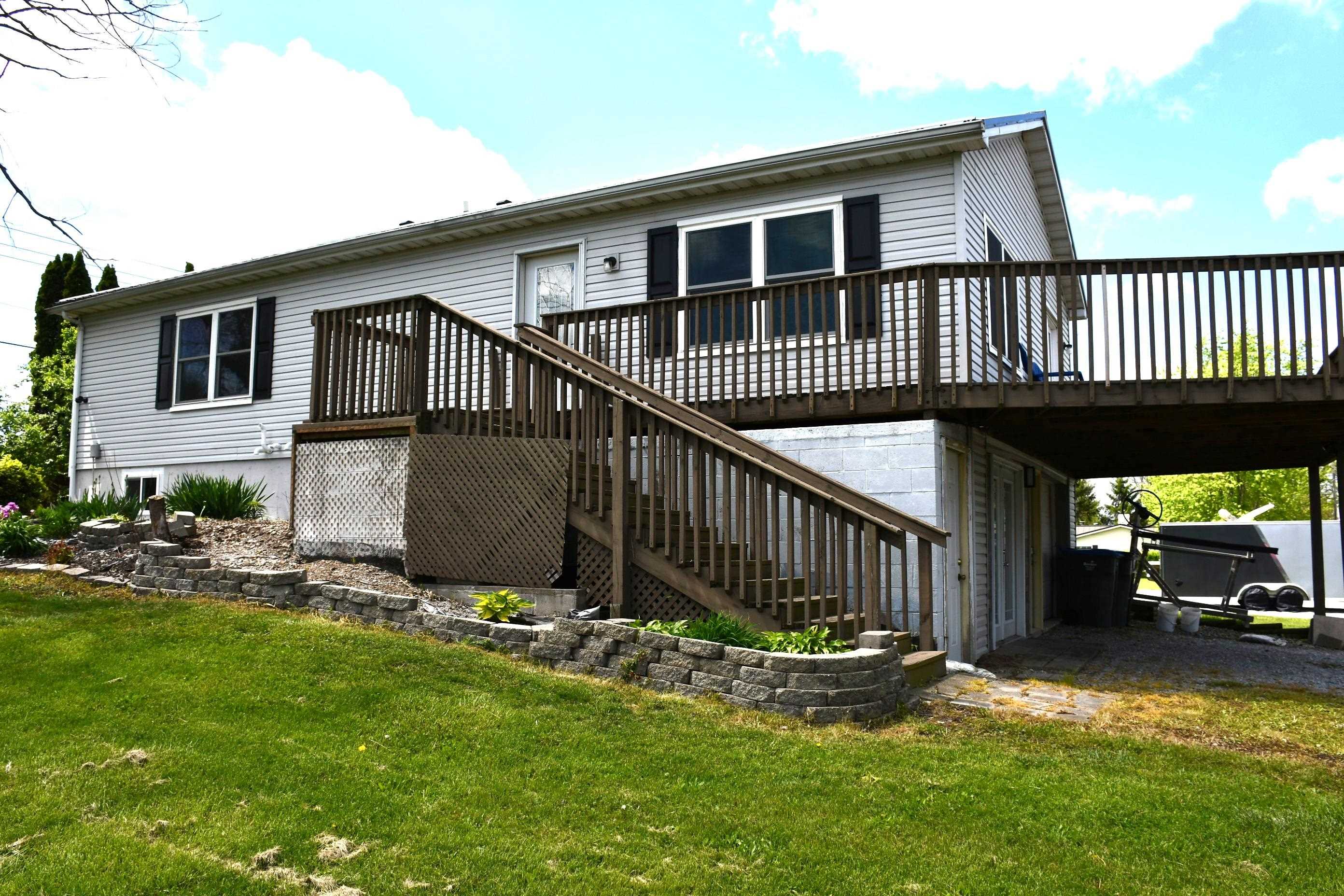 Split-level residence featuring light-colored siding and dark window shutters