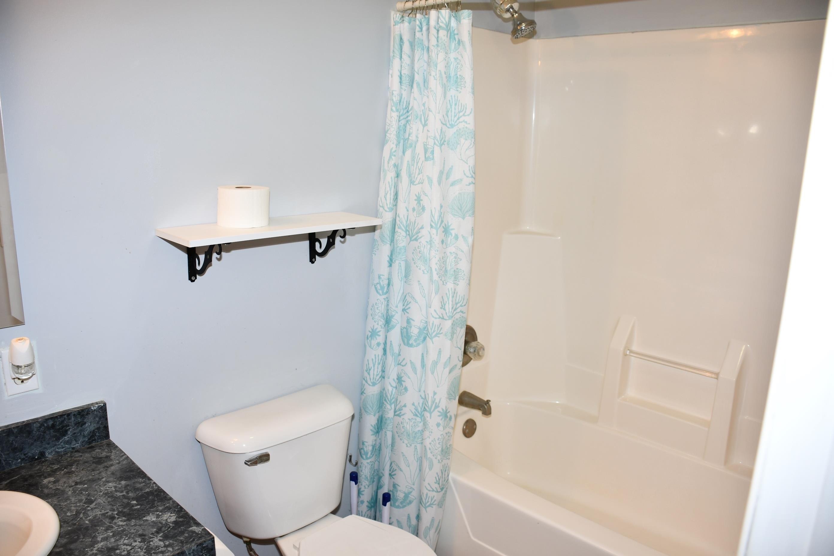 Bathroom featuring a white built-in tub and shower combination with a single shower head