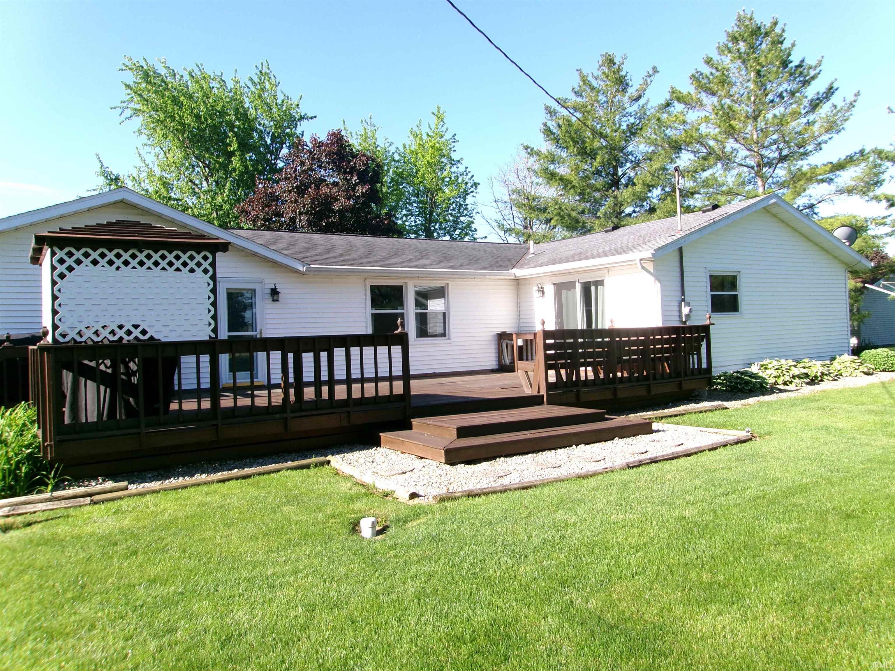 Expansive backyard featuring a multi-level wood deck with integrated privacy lattice, sliding glass door access, and a manicured lawn