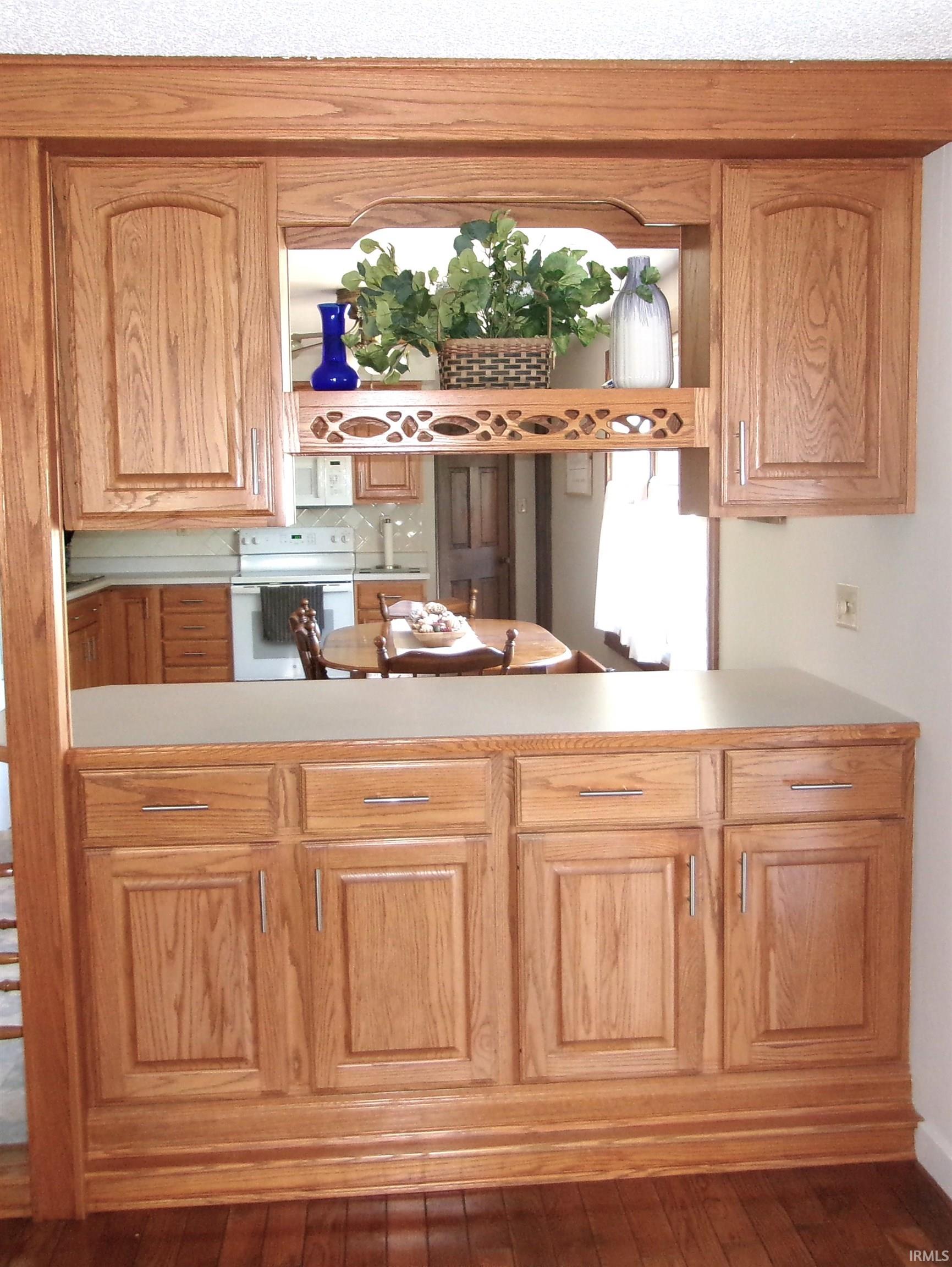 Wood-finish cabinetry with a built-in counter and decorative overhead shelving